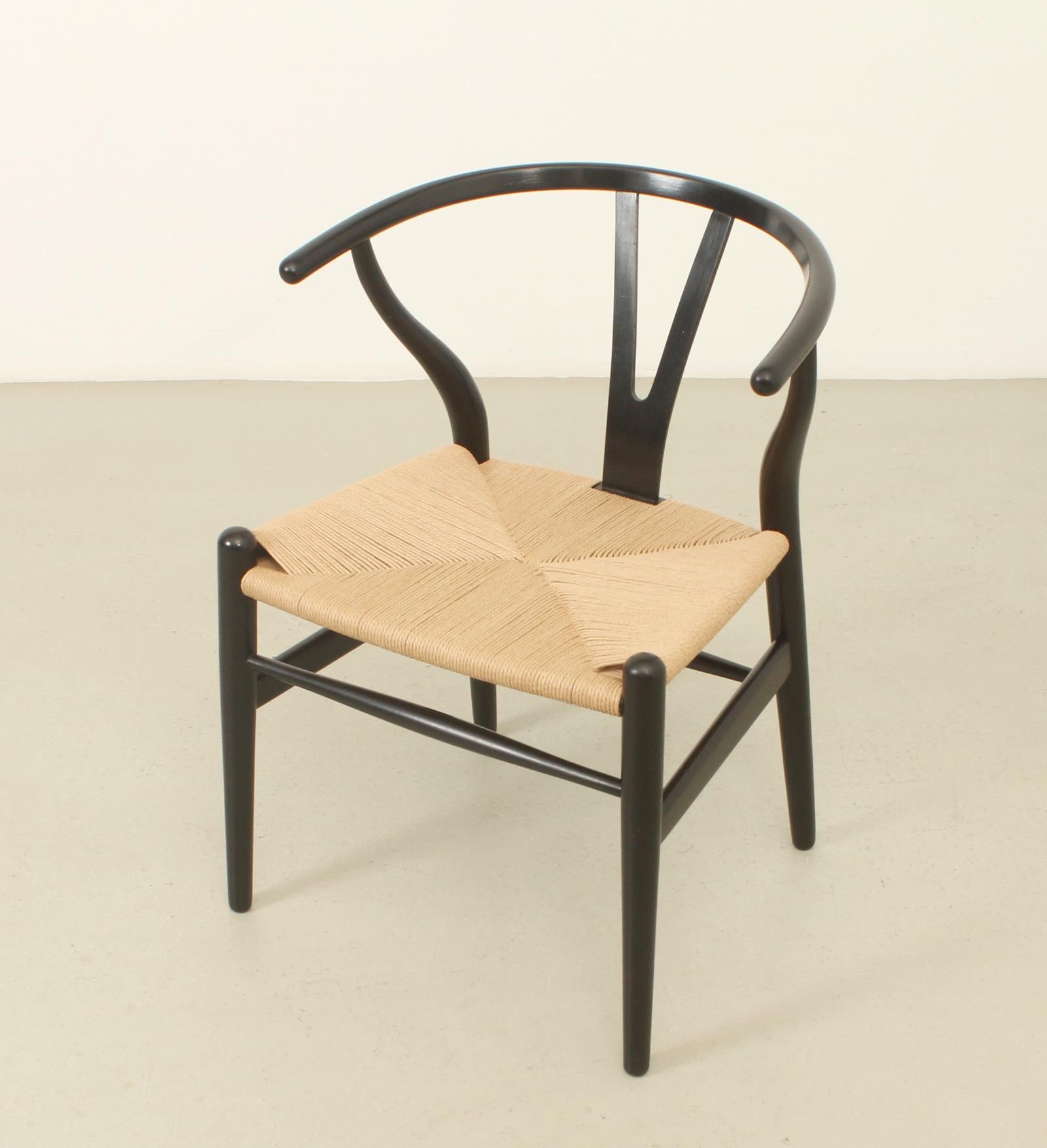 Wishbone chair model CH 24 designed in 1949 by Hans Wegner and produced in 1960 by Carl Hansen & Son, Denmark. Old edition in black lacquered beech wood frame with new papercord seat. 