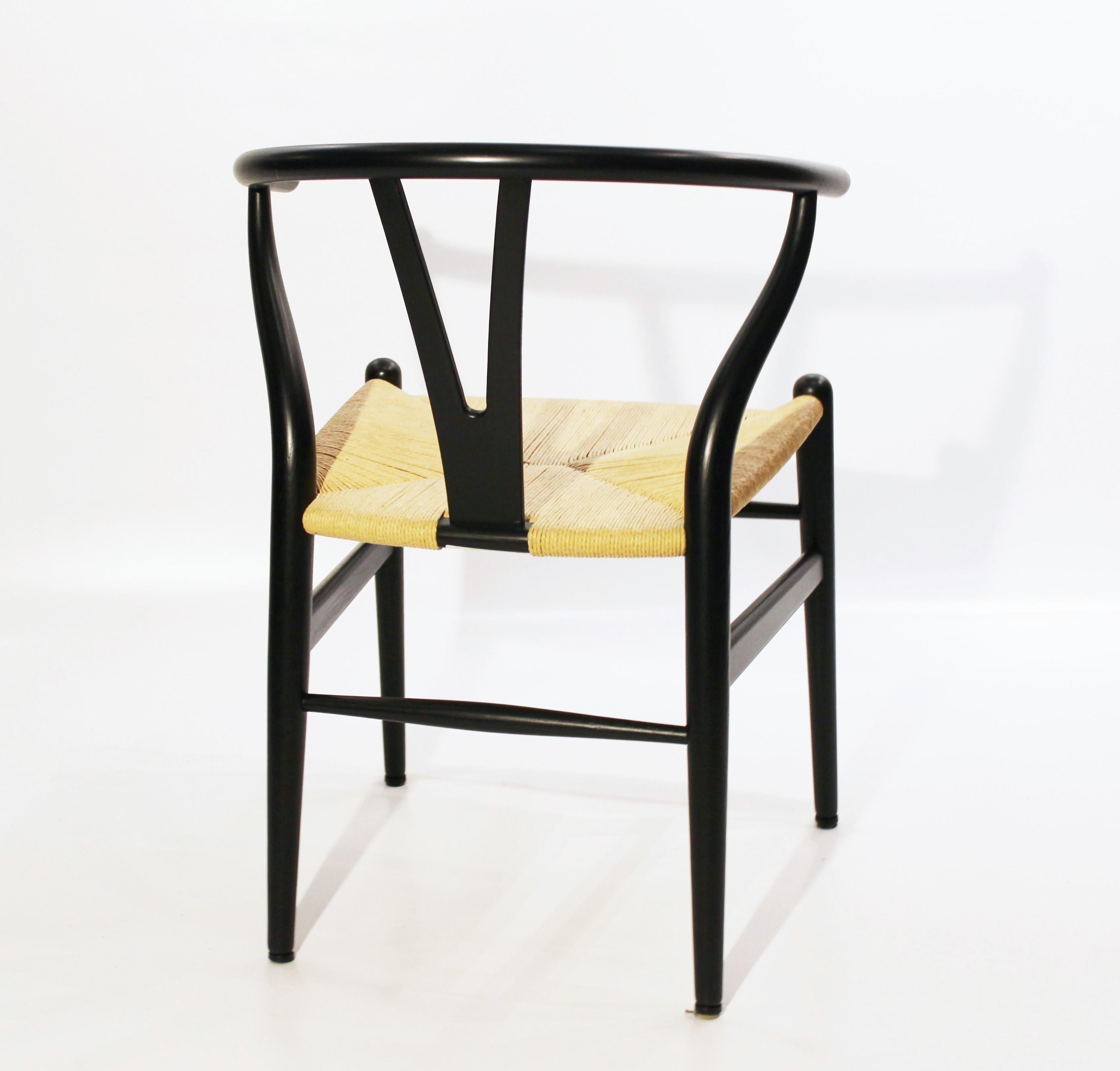 The Wishbone chairs, model CH24, designed by Hans J. Wegner and manufactured by Carl Hansen & Son, are exemplary pieces of Scandinavian Modern furniture. Crafted from black painted wood and featuring paper cord seating, these chairs showcase