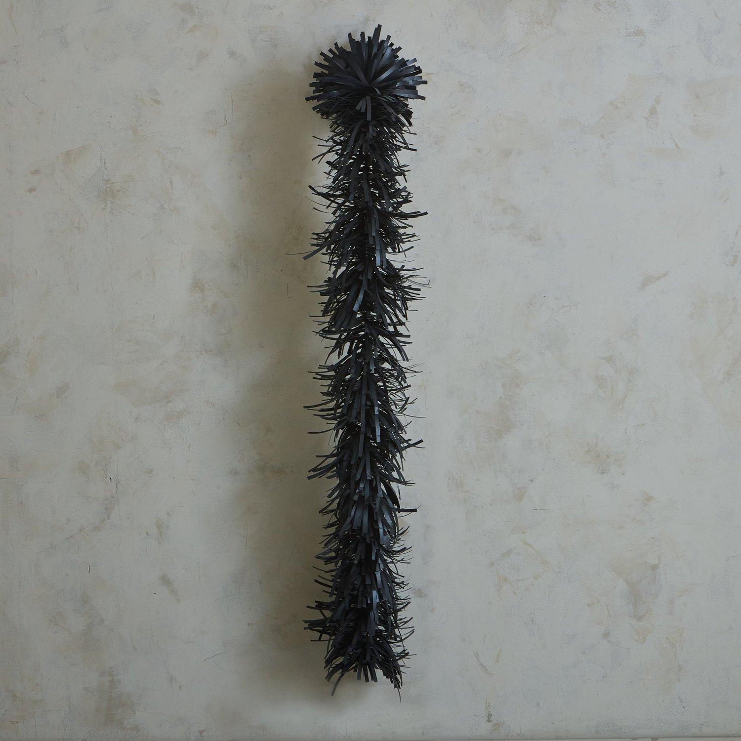 A textural wall sculpture made with black polypropylene straps which sprout from a tubular steel frame. This sculpture affixes to the wall and includes hanging hardware.

Erin Vincent is a Canadian artist who creates sculptural wall art and