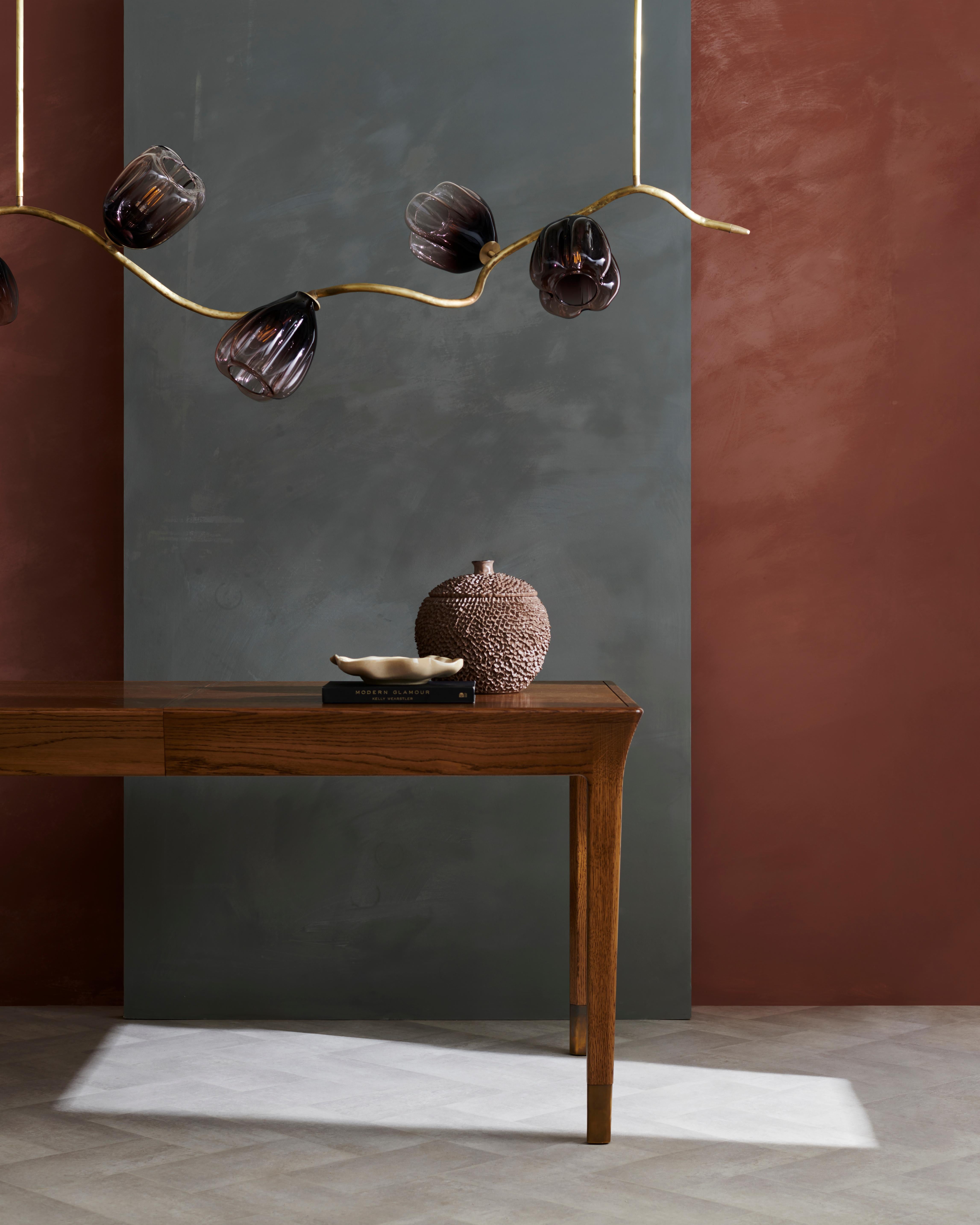 Ispirato alla leggiadra bellezza del glicine, il nostro lampadario Wisteria è caratterizzato da un ramo scultoreo in bronzo che si attorciglia e si trasforma, ornato da squisiti baccelli di vetro soffiato a mano con una delicata tonalità viola.