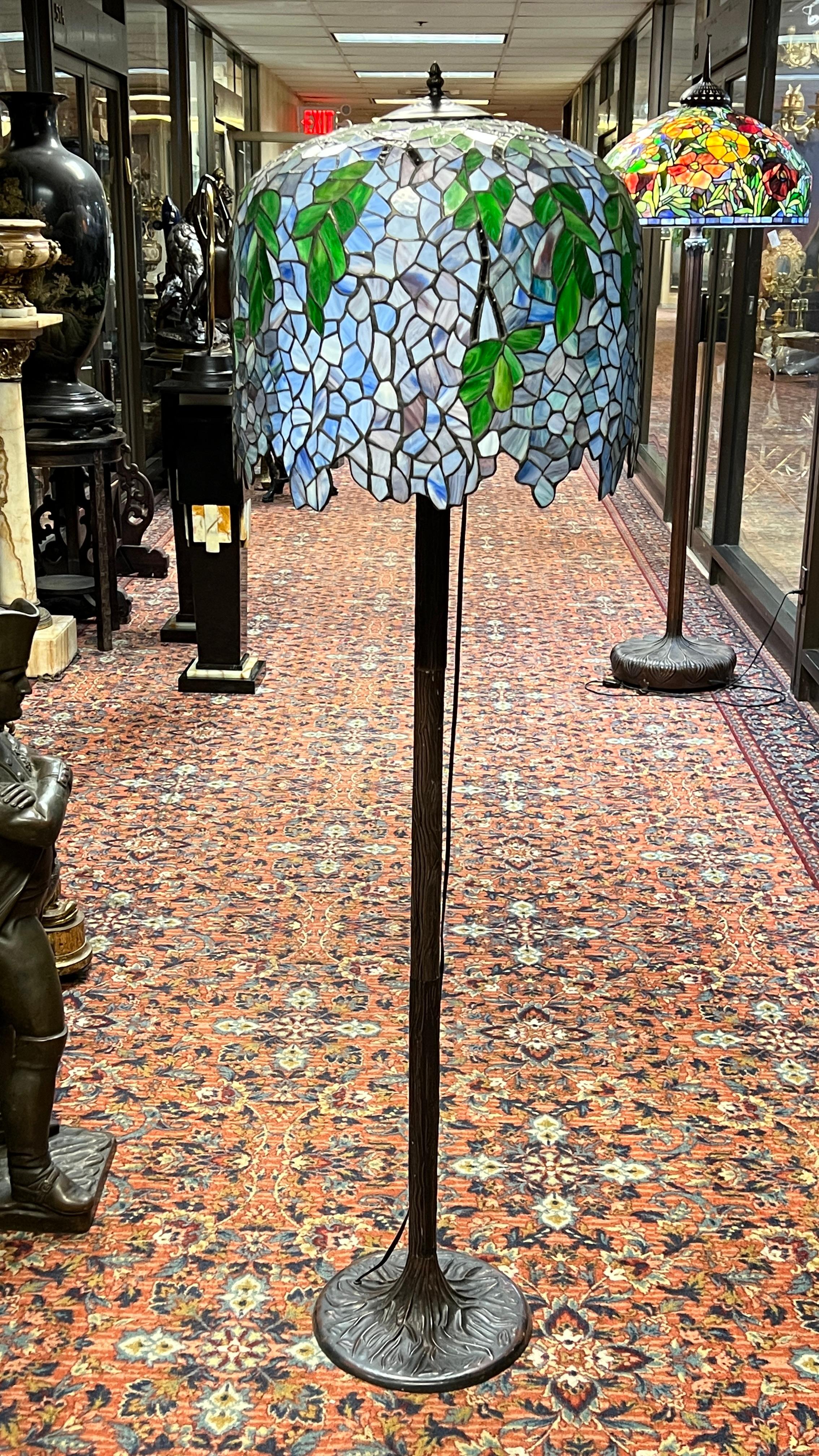 Lampada da terra vintage con paralume in vetro colorato raffigurante fiori di glicine secondo il disegno originale di Louis Comfort Tiffany.