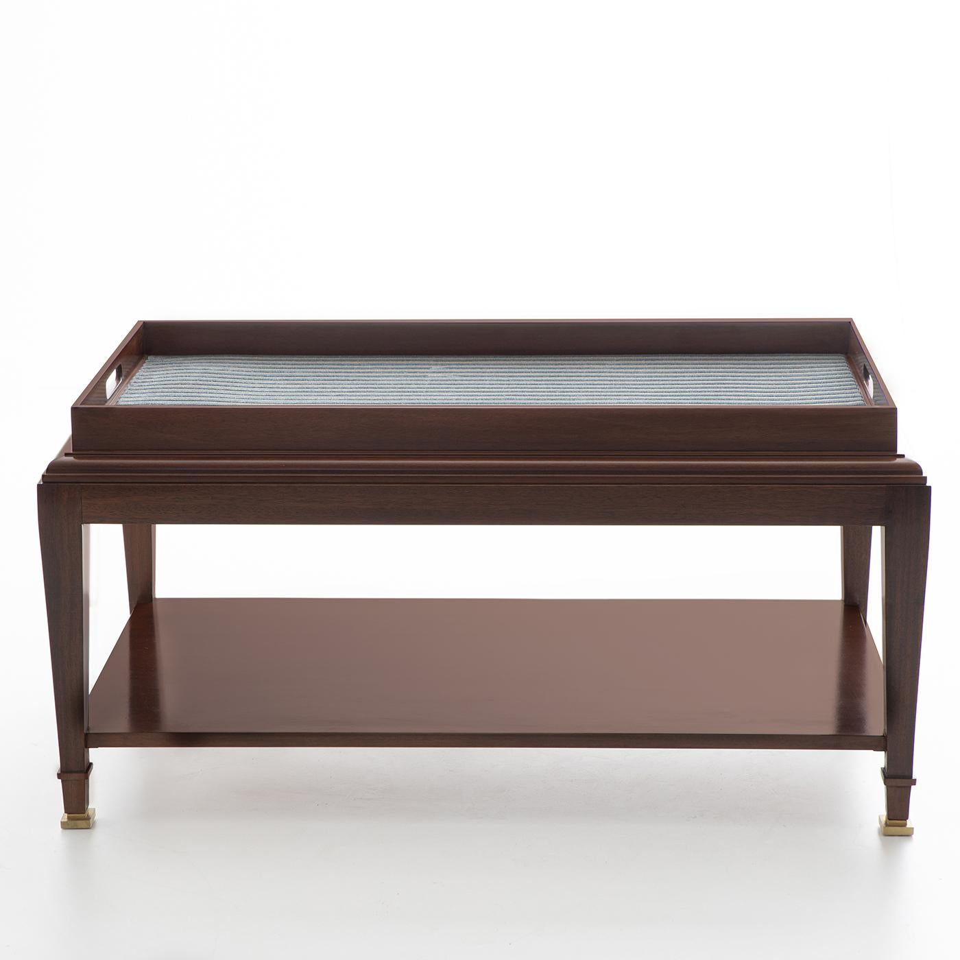 The elegant and versatile character of this precious coffee table in mahogany makes it a superb addition for classic or modern interiors. The wide top is enriched with a smooth fabric upholstery whose color can be customized to best fit any color