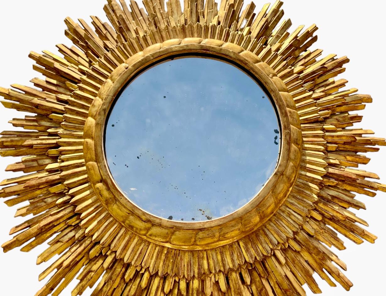 Witch mirror from the 50s/60s in gilded wood, also called sun mirror with its golden radiant rim. The curved surface of its mirror is called a witch's eye. It is in good condition.

Dimensions
Total diameter 76cm
Diameter only of the mirror
