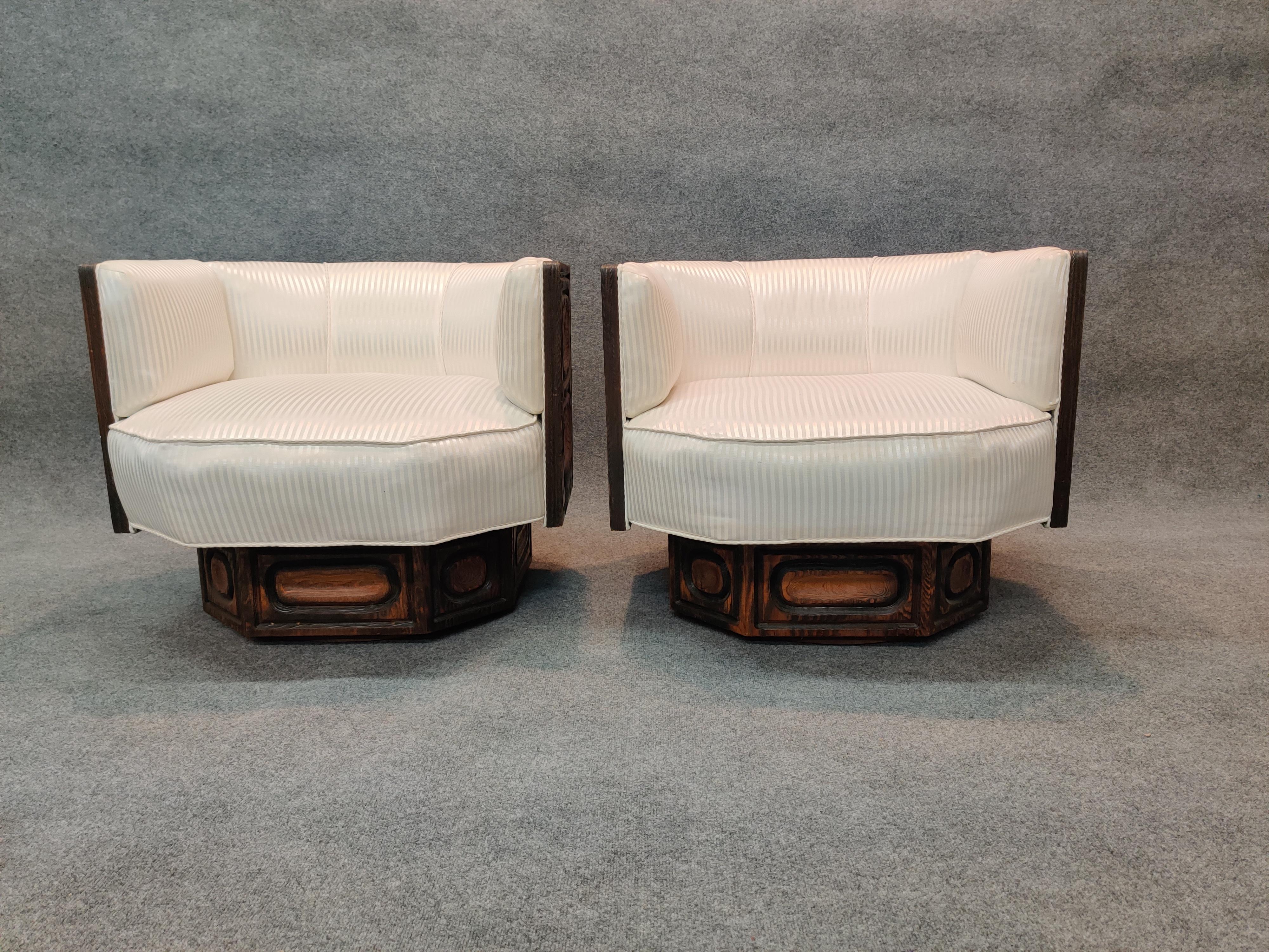 Pair of carved wood and striped fabric upholstry, brutalist geometric form lounge chairs on swivel bases. Attributed to the designs of William Westenhaver, who infused his creations with a unique blend of rustic appeal and graphic motifs. Likely