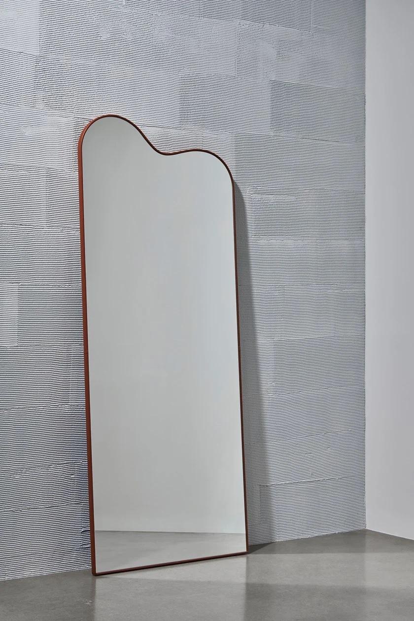 Wooden Construction, covered with leather.- Nappa Mocca leather
En ouvert is the French name given to an open body alignment in which a ballet dancer faces the audience downstage. OUVERT, a 199cm high mirror, presents an equally open and