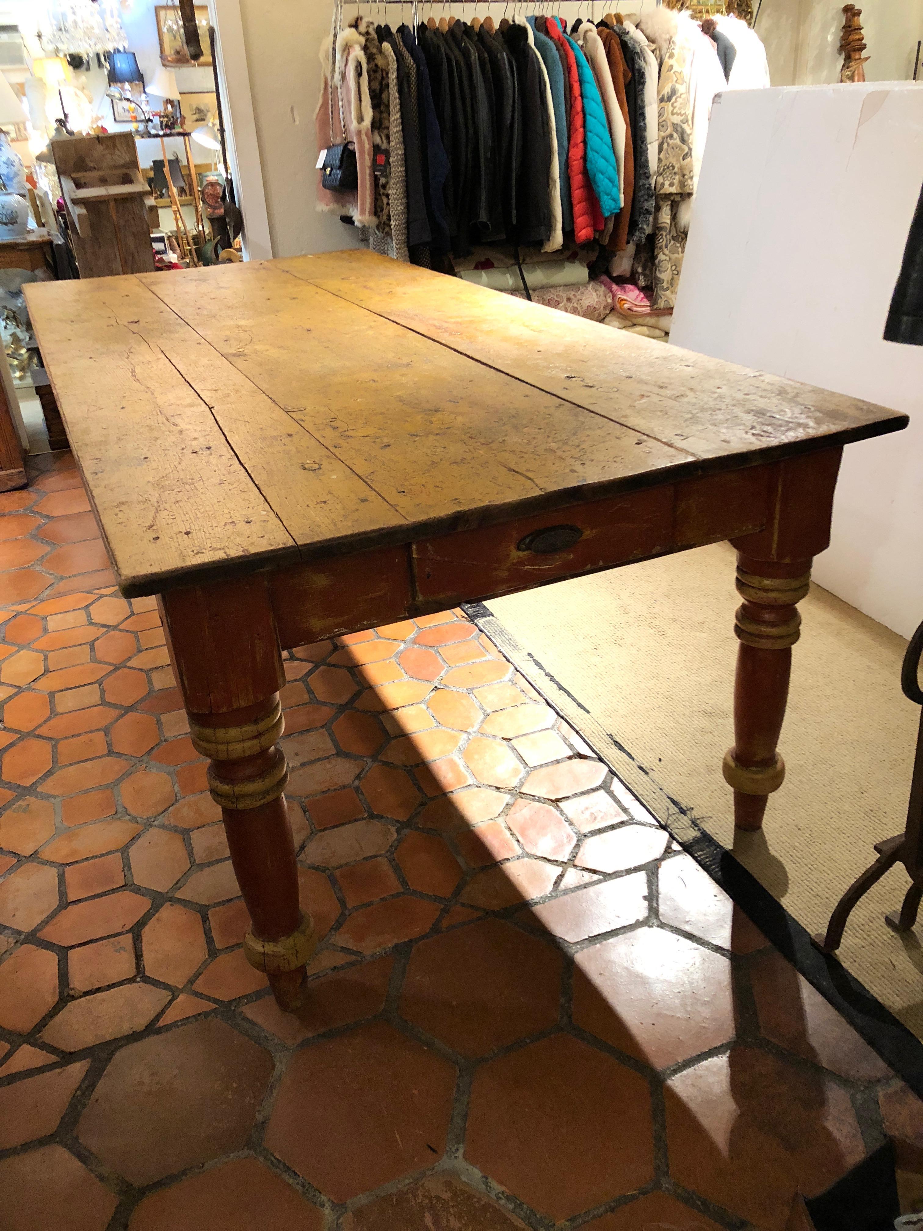 Amazing one of a kind antique Maine farm table, very large at almost 8 feet long, with gorgeous original paint and patina in warm tones of mustard, brown and red, having plank top and big turned legs as well as two drawers at each end. Apron height
