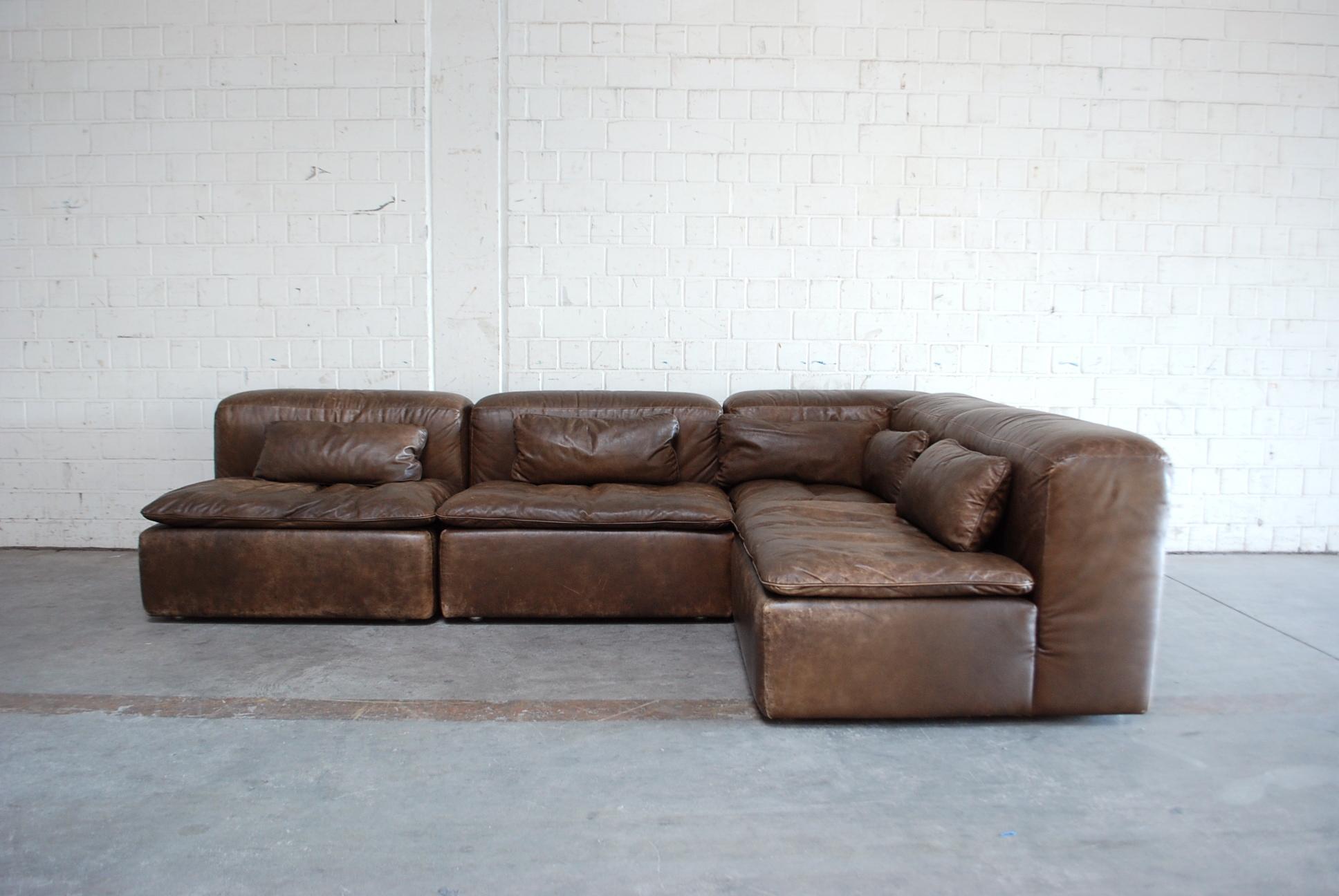 This vintage module sofa was made by German architect Ernst Martin Dettinger for WK Möbel / WK Wohnen.
The name is model WK 550.
It consists of 4 elements including 1 corner and 3 single elements with 5 small cushions and it´s in brown aniline