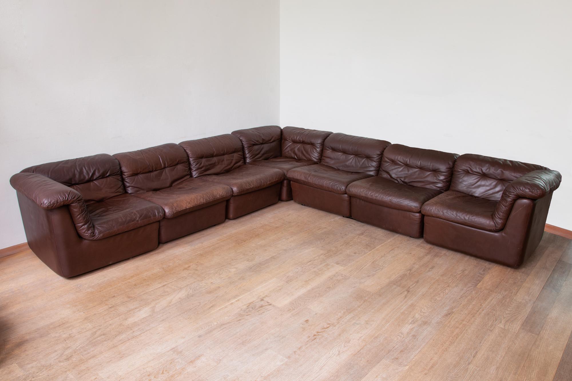 Large modular tufted leather sofa.
Composed of 3 corner pieces and 4 armless middle pieces and 2 decorative cushions. Can be set up in many different combinations to create one large sofa, or even use two sections as lounge chairs. The cushions are
