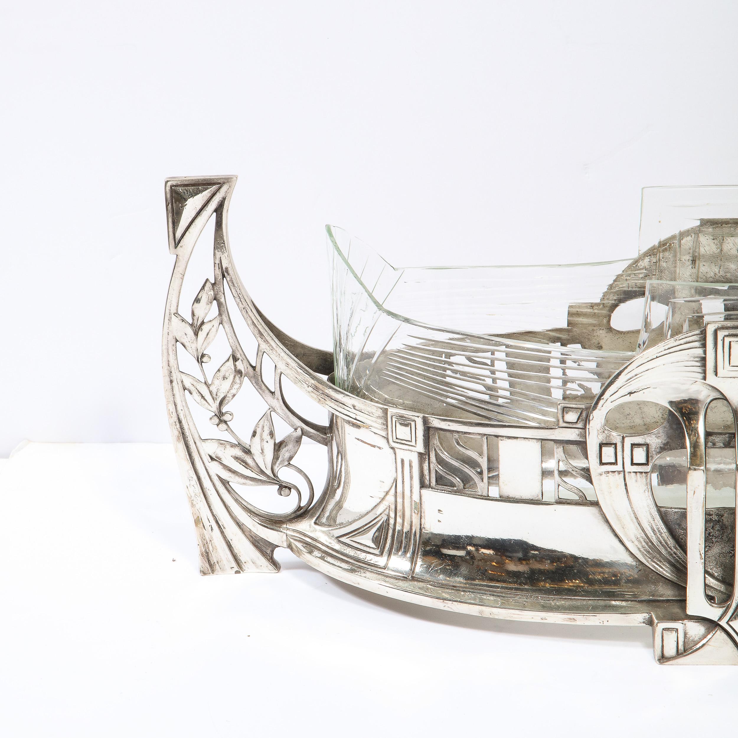 This elegant Art Deco silverplate center piece was realized by the esteemed atelier of WMF Ikora in Germany circa 1925. Resembling a stylized Adrestia, or ancient Greek ship, the piece features streamlined open form sides with foliate detailing;