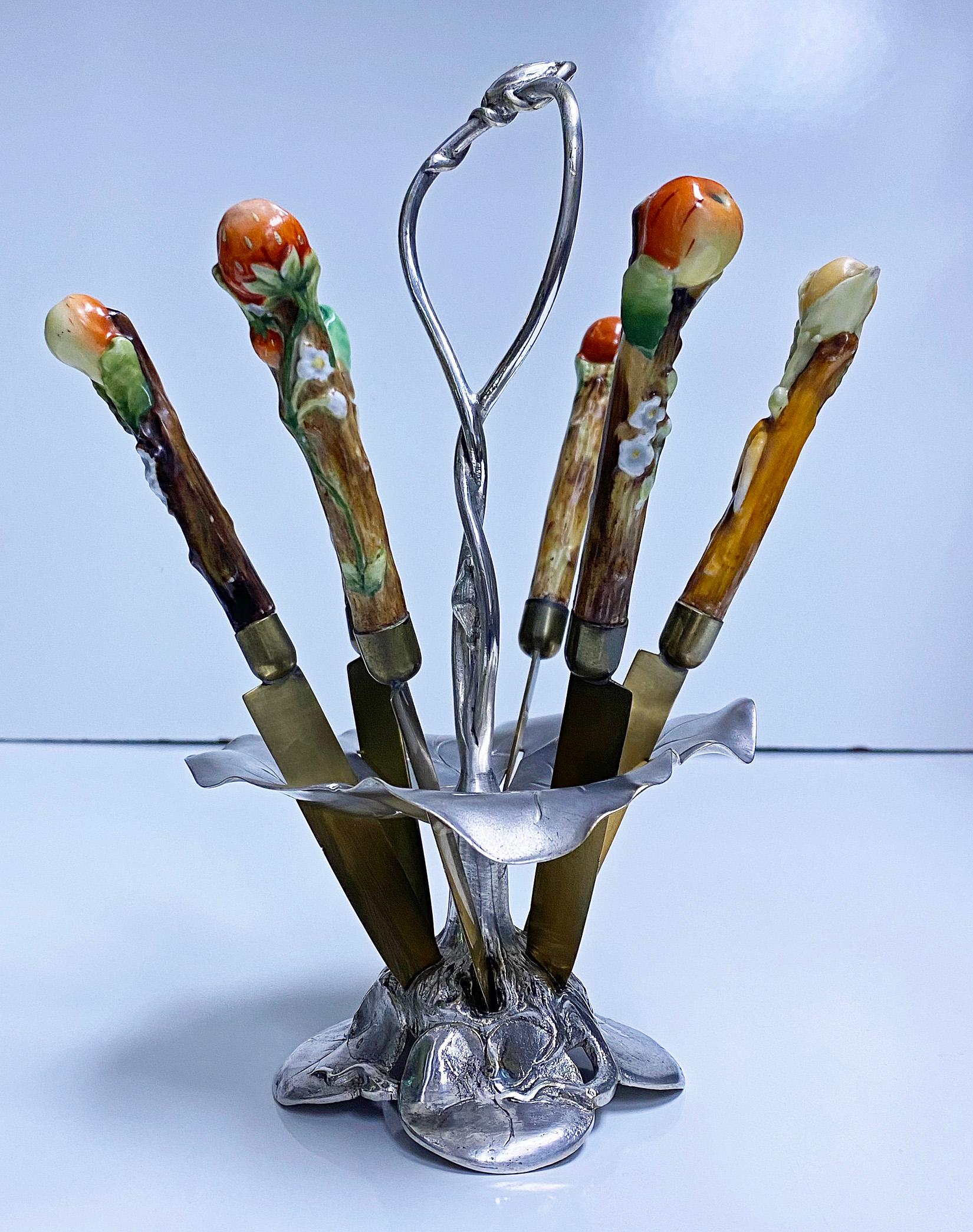 Very rare WMF Art Nouveau fruit knife stand, Germany, circa 1900. The stand of leaf base foliate section and handle design complete with six slotted fruit pattern china handled bronze blade knives. Each handle to knife depicting a different fruit
