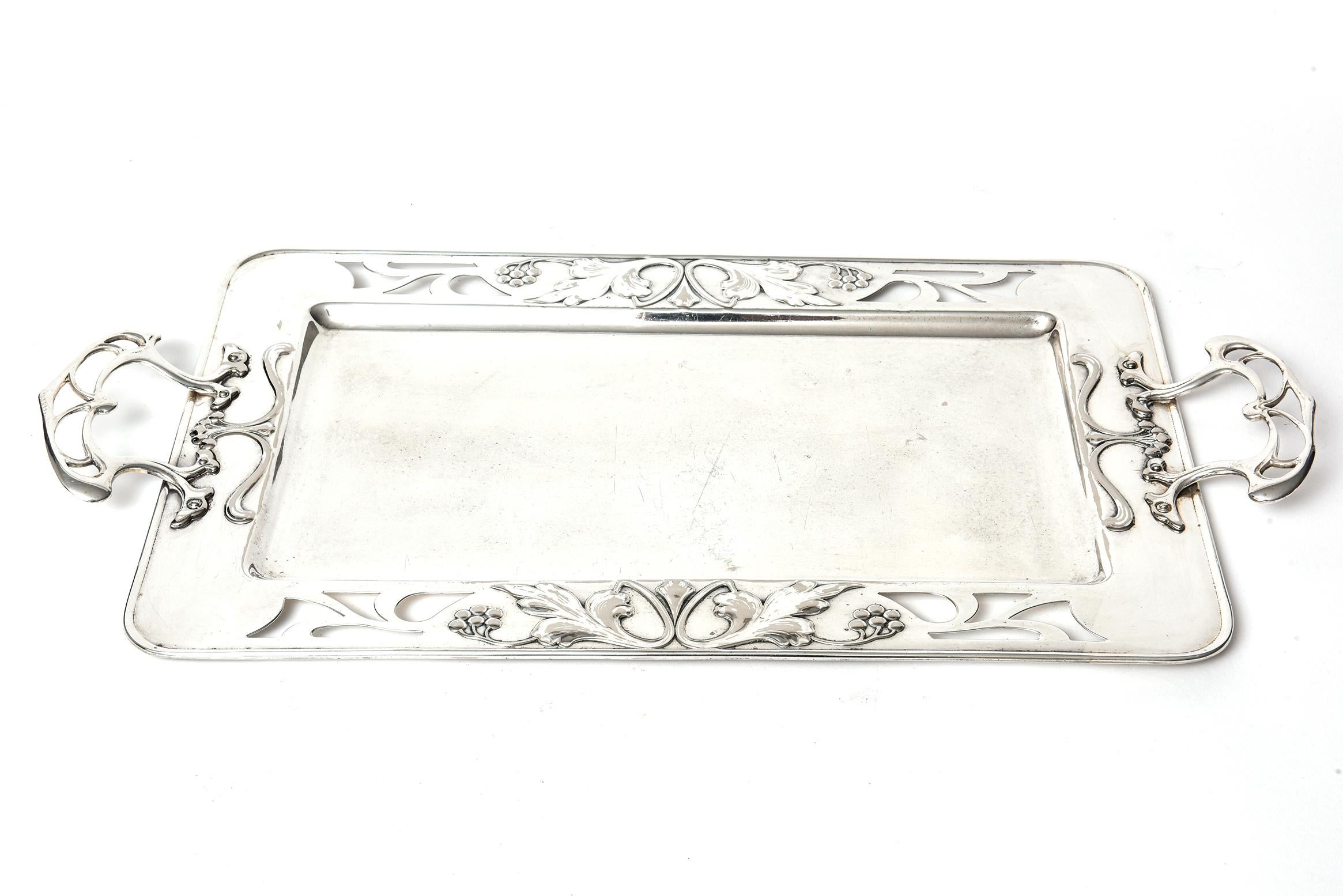 WMF Württembergische Metallwarenfabrik Art Nouveau silver plate rectangular serving tray with pierced sides and leaf and berry relief design. The decorative handles are an openwork stylized art nouveau design. 

Württembergische Metallwarenfabrik