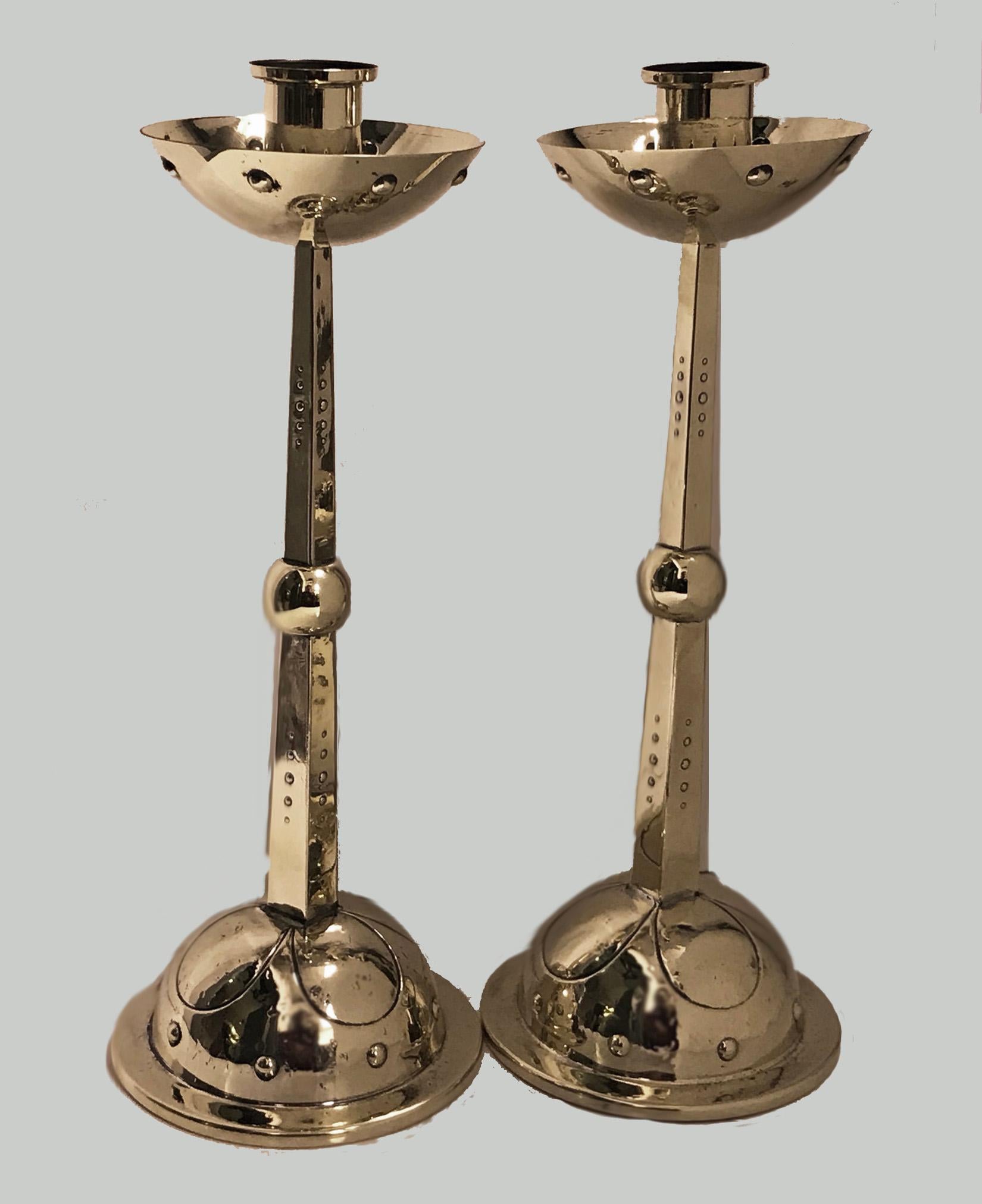 WMF Arts & Crafts Art Nouveau Jugendstil candlesticks, Germany, circa 1900. The brass candlesticks each on dome stylized and rivet surround bases, tapered quadrilateral stems centering a bulbous sphere, the polished nozzle supporting deep well drip