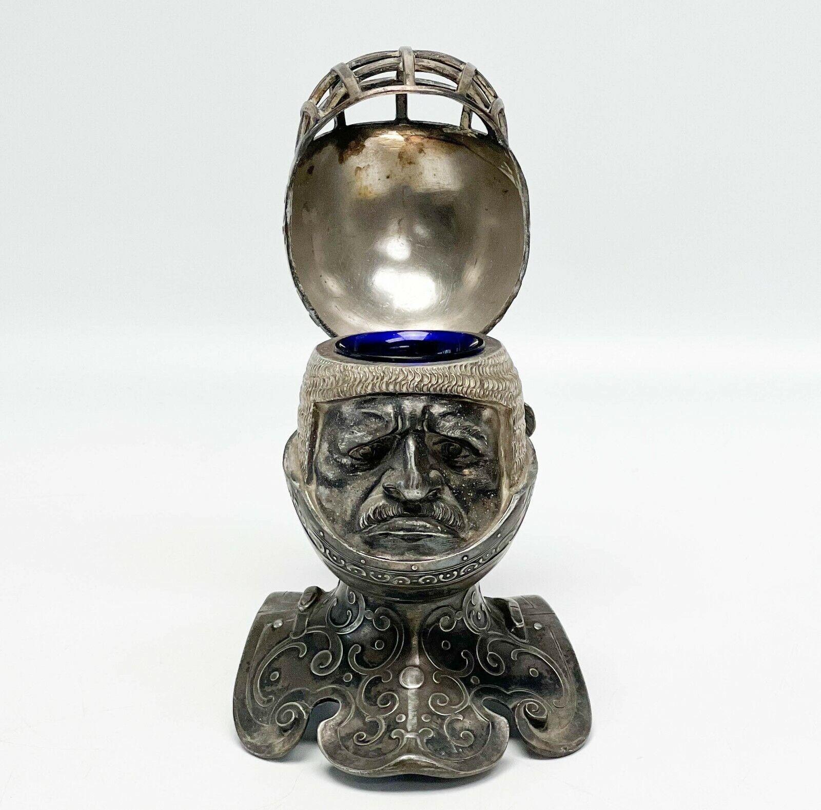 WMF Britannia Silberblech mittelalterliche Ritterbüste modelliertes Tintenfass mit Einlage, um 1900

Figuraler Ritterkopf mit aufklappbarem Helm, der das Gesicht und das Tintenfass mit kobaltblauer Glaseinlage freigibt. Unterseite mit der seltenen