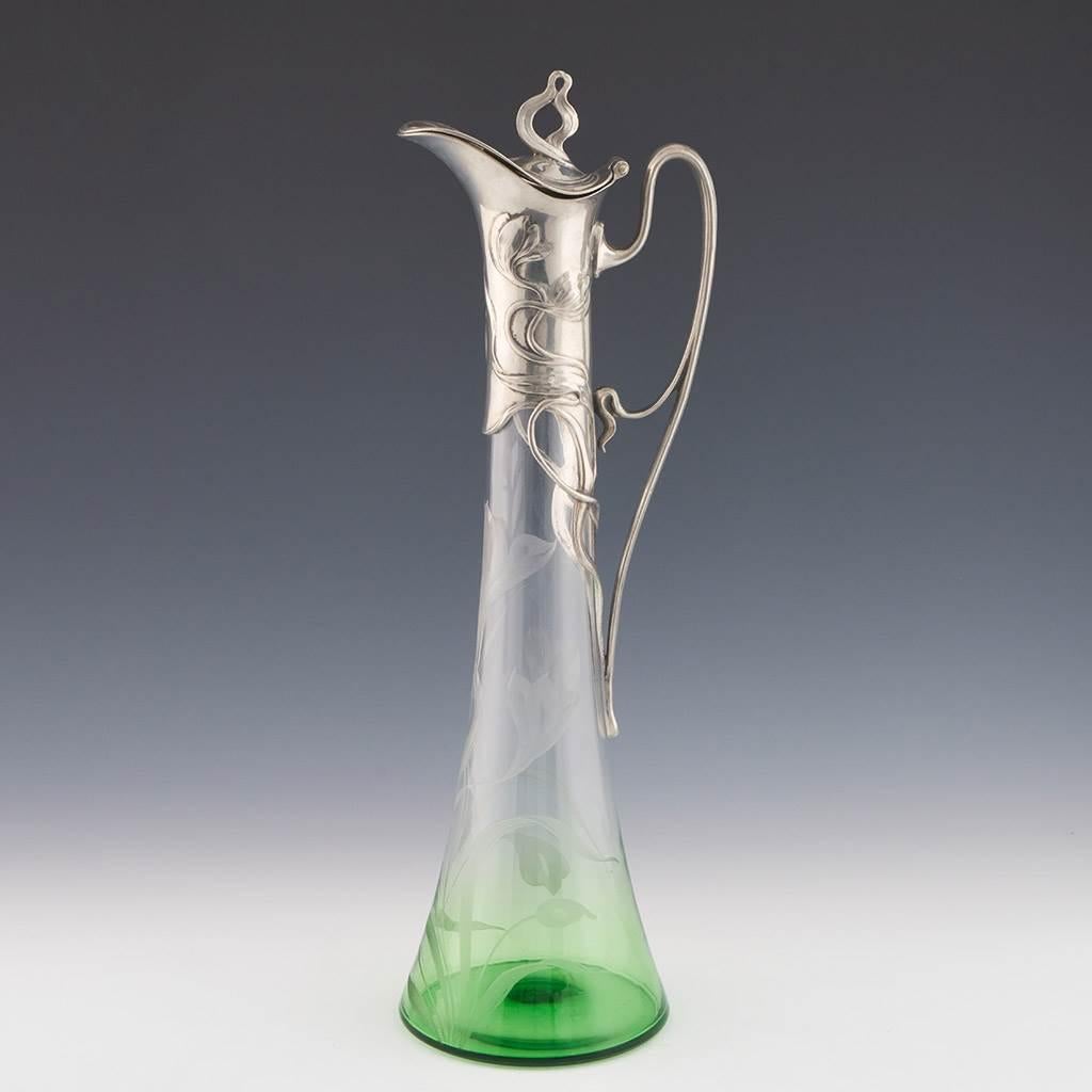 Heading : WMF claret jug c1905
Date : c1906
Origin : Geislingen an der Steige
Bowl Features : Graduated clear and green glass bowl with floral engraving. Silver plated art nouveau handle and cover.
Marks : WMF lozenge mark. I/O silver plate mark and