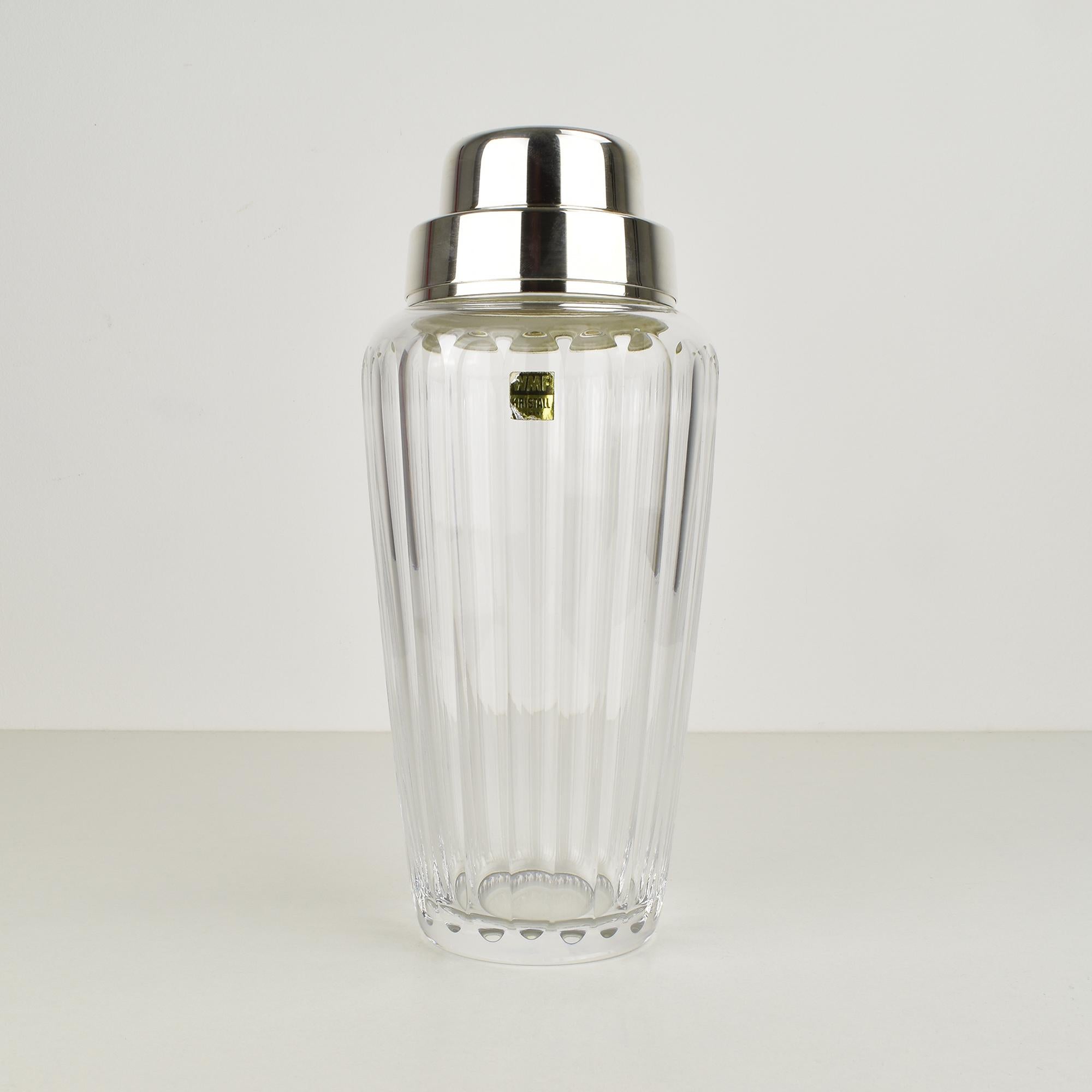 Questo splendido shaker da cocktail di WMF risale agli anni '60 e presenta una splendida combinazione di cristallo tagliato e metallo argentato. Il corpo dello shaker presenta un classico design a coste che non solo ne migliora l'estetica, ma offre