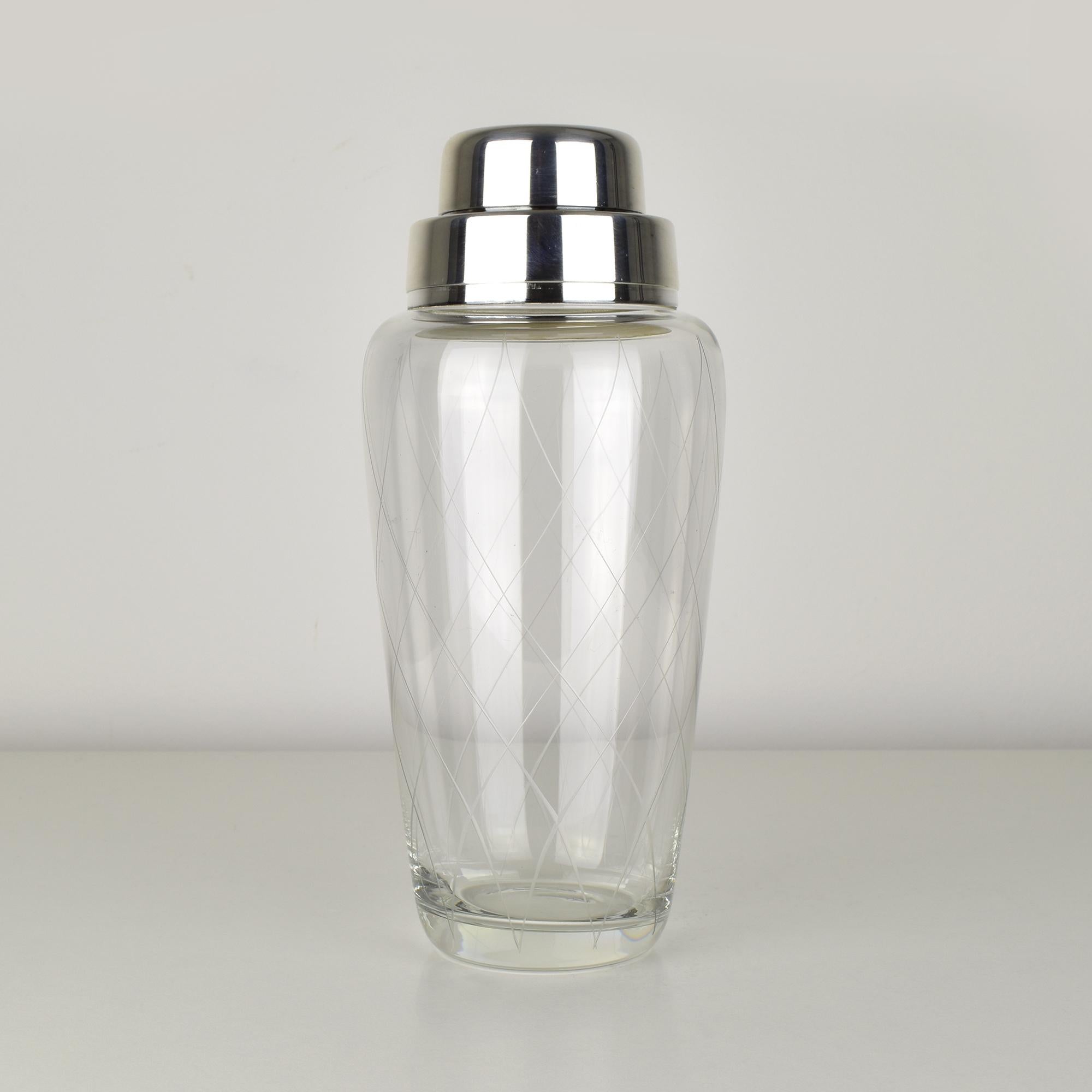 Shaker da cocktail WMF vintage degli anni '60. Il corpo è realizzato in vetro trasparente con un elegante motivo a diamante tagliato a ruota, che gli conferisce un'estetica raffinata e di metà secolo. La parte superiore e il coperchio sono in