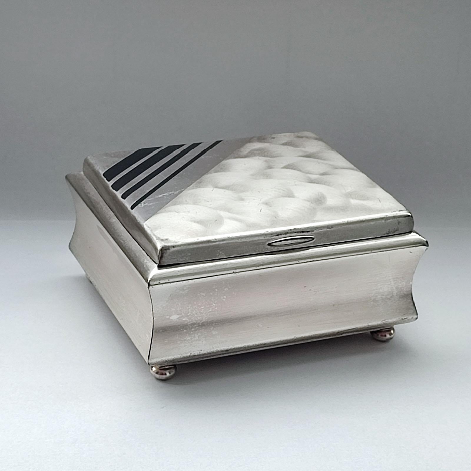 Sophisticated square box with hinged lid by WMF for Ikora Collection. Silver-plated Art Deco geometric shape, its interior is lined with cedar planks. A lovely black enamel banded motif adorns its top. A perfect piece to store keys or small objects