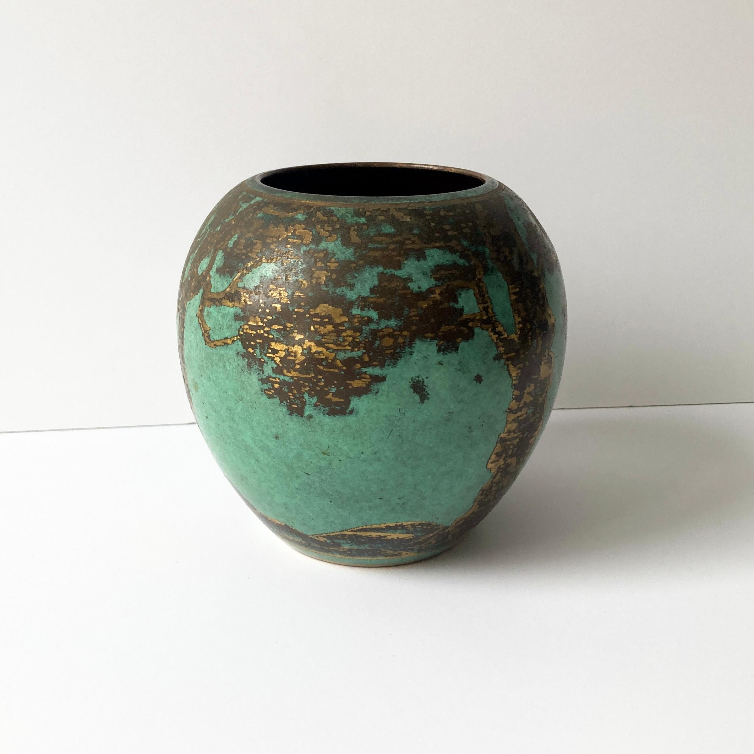 Raro vaso arrotondato in metallo WMF Ikora degli anni '30. Il metallo verde turchese patinato contrasta meravigliosamente con il disegno dorato di alberi e rami. Si tratta di un pezzo straordinario che fa bella mostra di sé come parte di un gruppo,