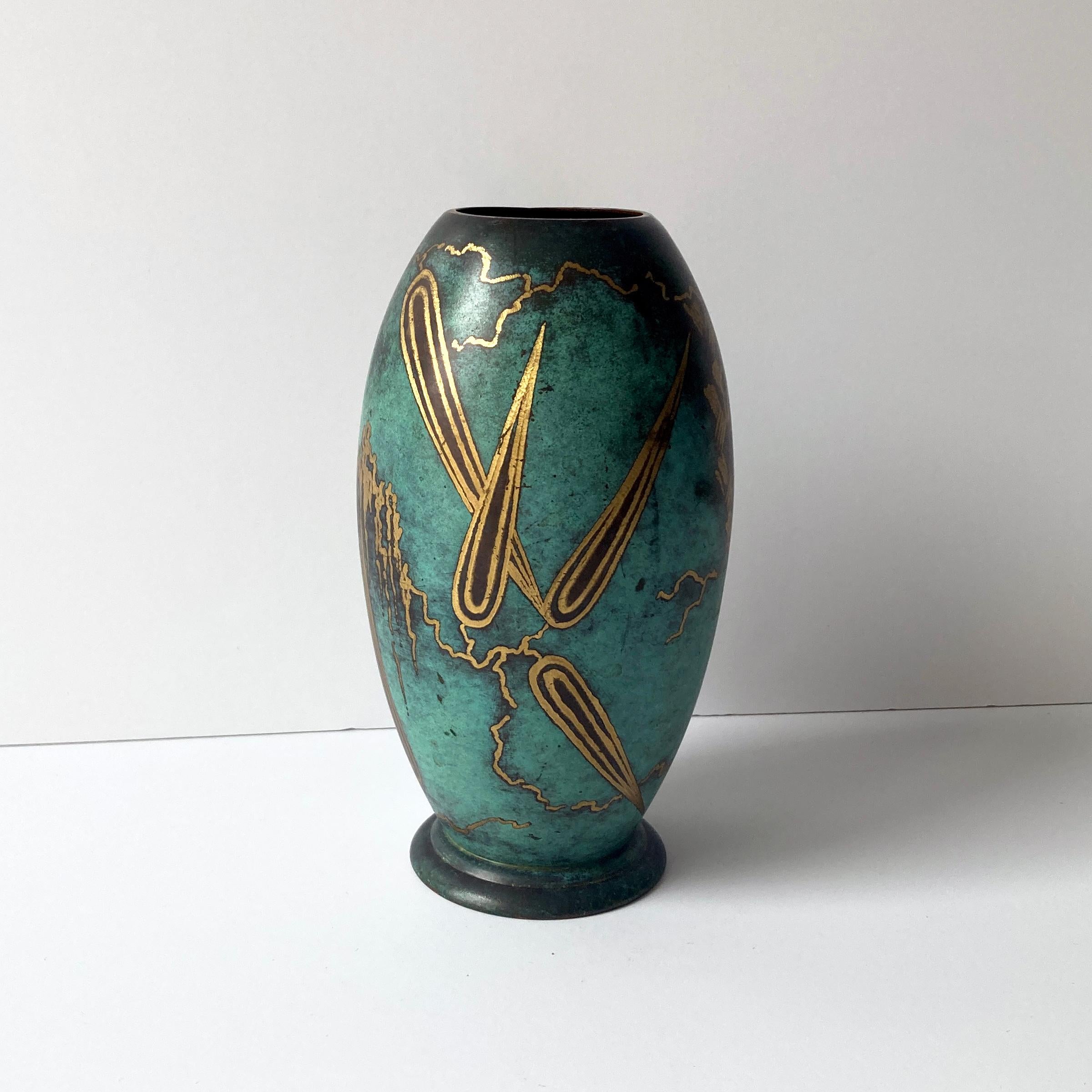 Stunning WMF Ikora metal rounded vase from the 1930s. The patinated turquoise green metal contrasts beautifully with the gold abstract leaf design. This is a stunning piece that looks wonderful as part of a group, or independently on a credenza or
