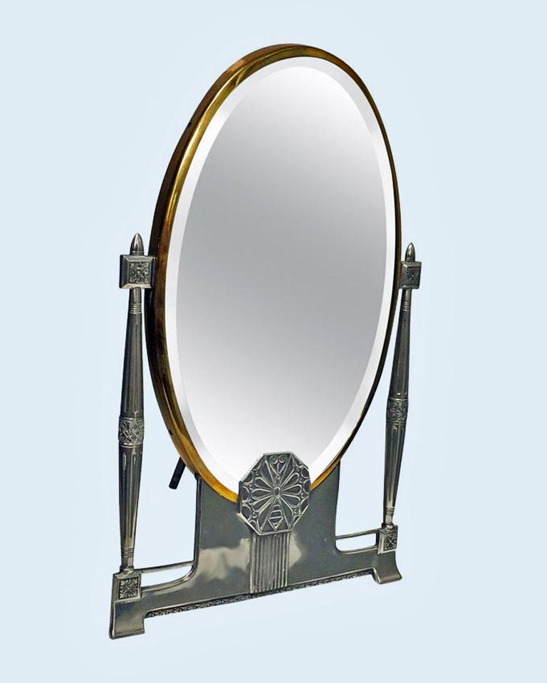 W.M.F Mirror, oval shape in silver plate and brass with supports and lower section of celtic decorated accents WMF beehive mark, original back and spiral easel, easel back also marked, circa 1910. Measures: 15 ½ x 10 inches.