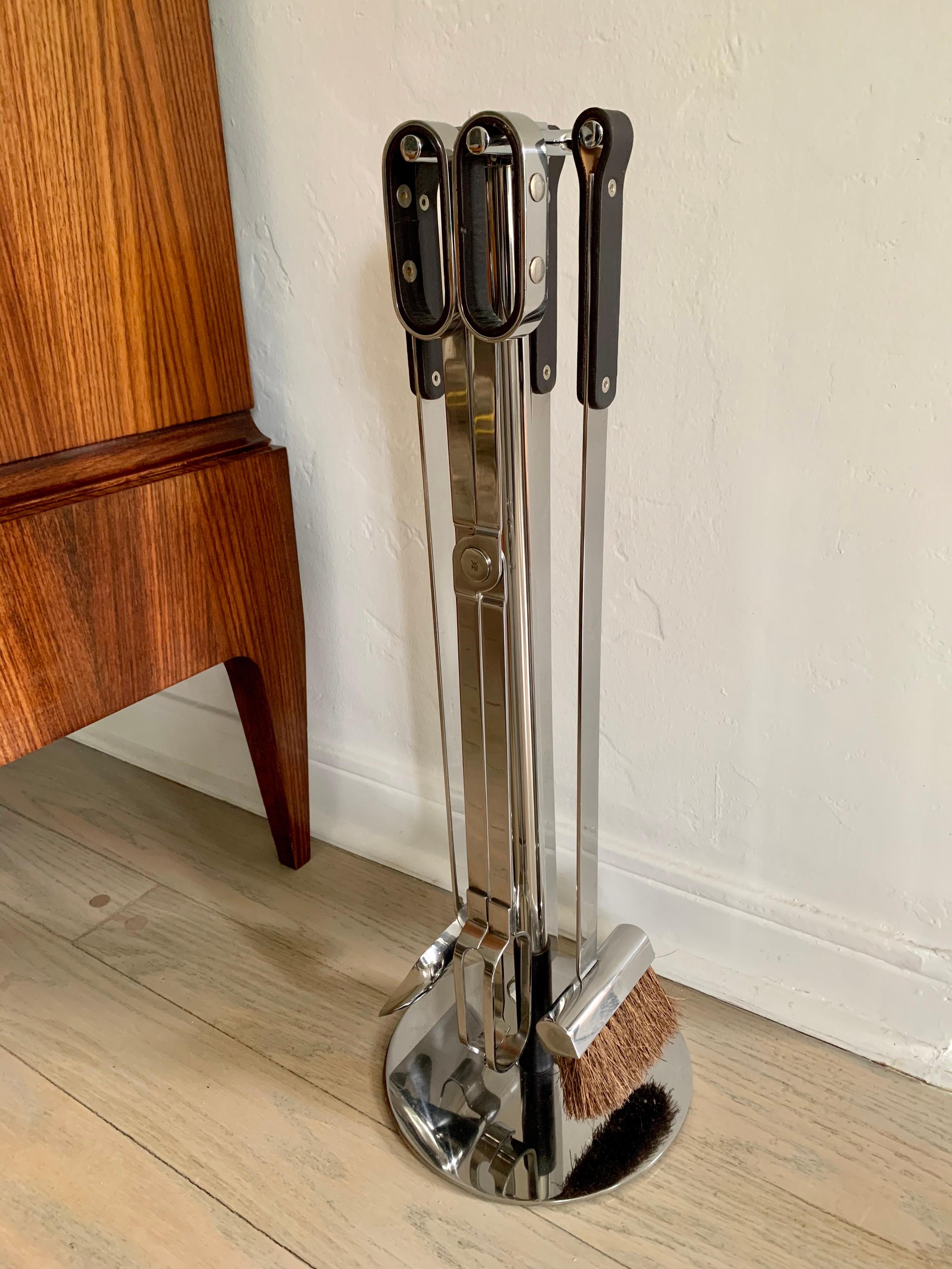 WMF modernist chrome and saddle leather trimmed fireplace tools (tongs, ash sweep, poker and shovel on stand). All pieces marked WMF.

Provenance: property of prominent family in Oyster Bay, New York.