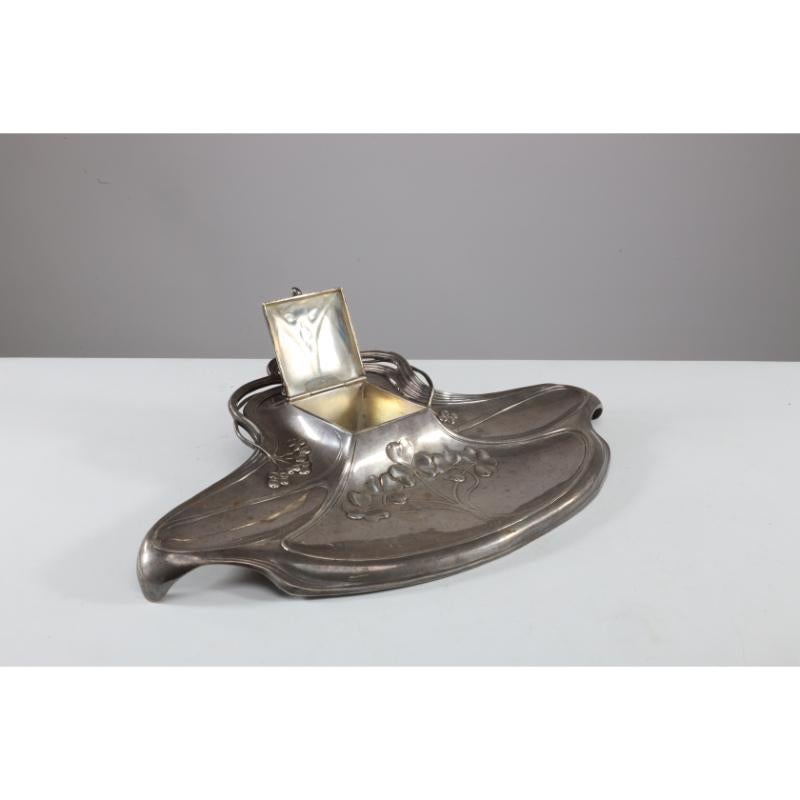 WMF. Calamaio secessionista in peltro Art Nouveau. Germania. Il calamaio ha una forma organica rettangolare con trifogli stilizzati sul bordo anteriore, una parte frontale liscia e profonda e sezioni laterali più piccole, la sezione del calamaio