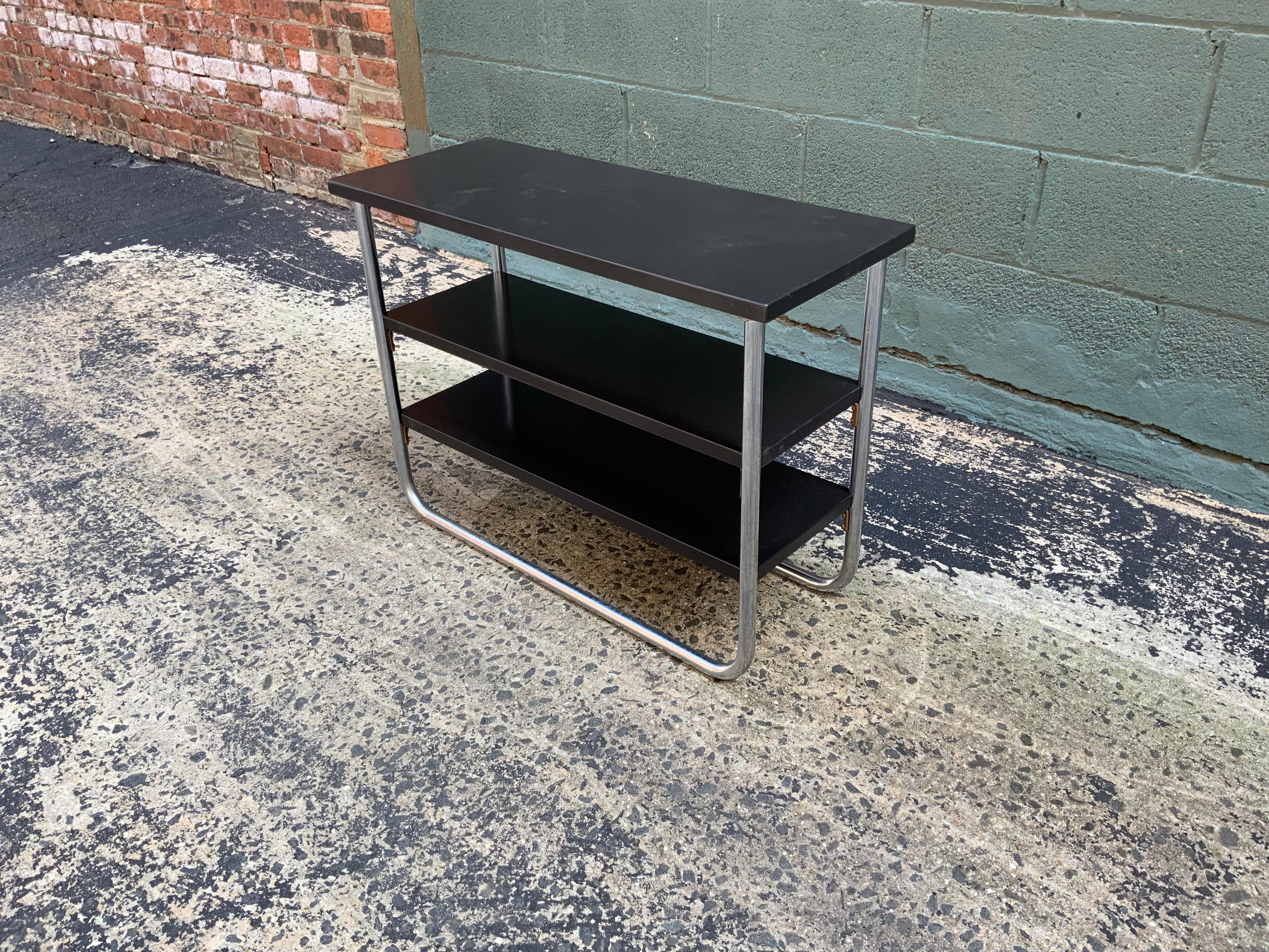 Tubular chrome and black lacquer three tiered table designed by Wolfgang Hoffman for Lloyd, circa 1930-1940.

Measures: 12” deep x 30” x 22” high.