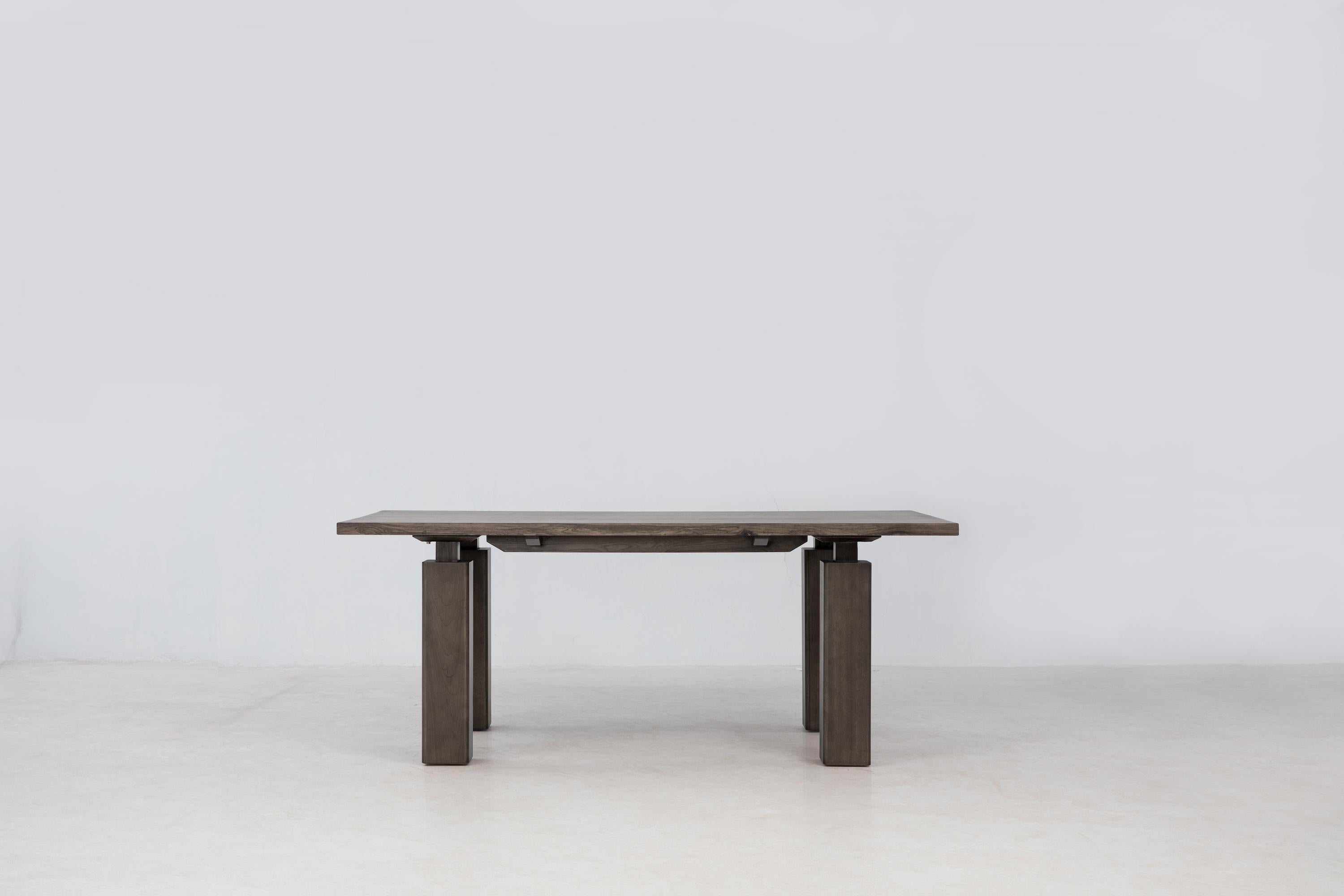 

The Wolo Dining Table features the beautiful grain and luminescent sheen of Makata Wood, focusing on contrast as a guiding concept. The columnar legs feature thick legs attached with thin connective tissue for a sculptural feel. The simple