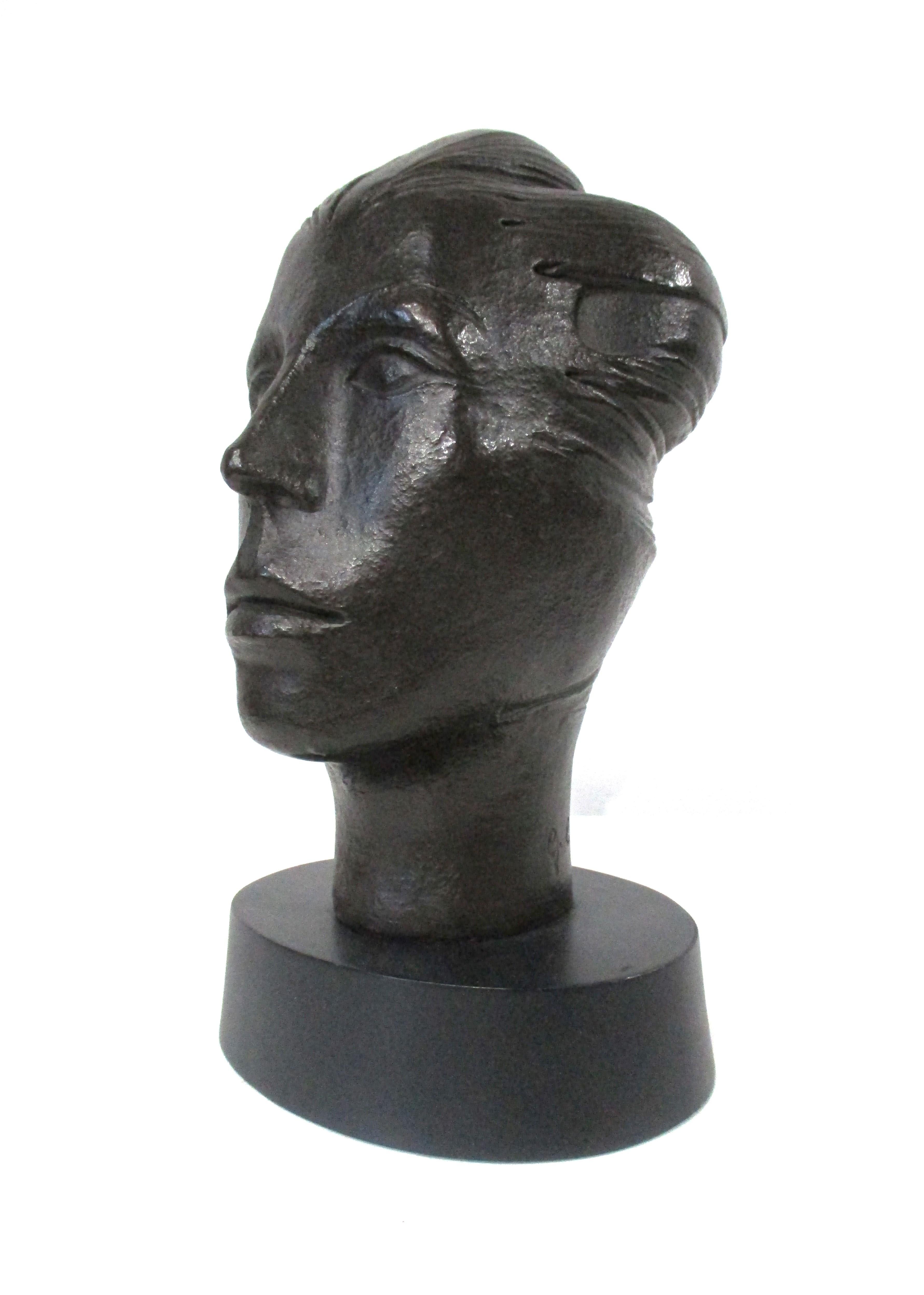 A sculpture of a strong woman's head in a dark bronze styled finish with satin black oval base . This cast composite bust has great details with a wind swept feel of freedom and confidence signed and numbered by the artist to the back of the neck