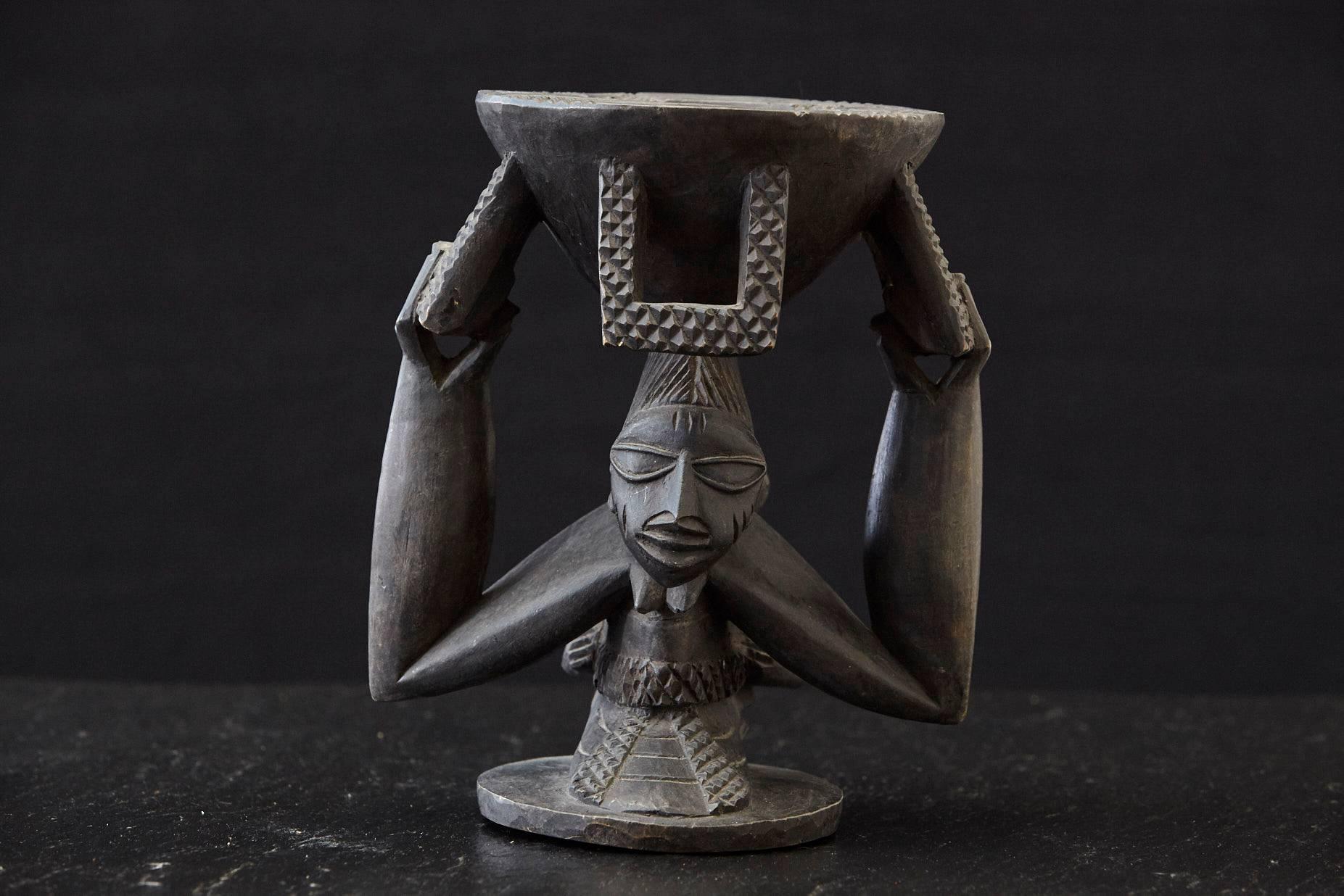 Carved wooden kola nut holder, depicting a woman carrying a baby in a papoose and holding a bowl overhead, from Abeokuta, Nigeria, 1950s

There is a small crack in the wood on one side, please refer to the photos. 

The numbers is the inventory