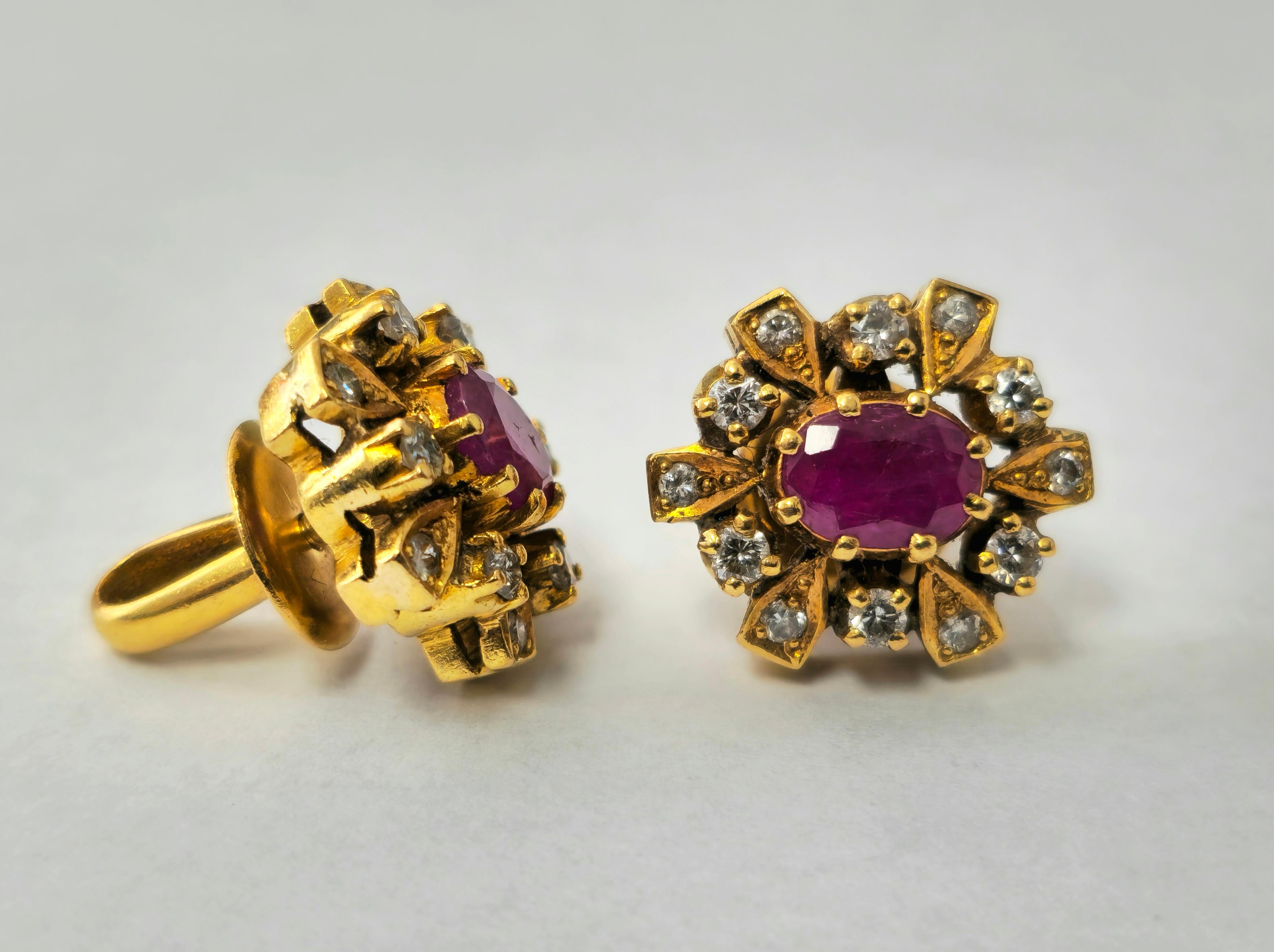 Fashioned in 18K yellow gold, these exquisite earrings feature a stunning 1.20 carat oval-shaped ruby, surrounded by a total of 1.03 carats of round single-cut diamonds. The diamonds boast SI1 clarity and G color, accentuating the allure of the