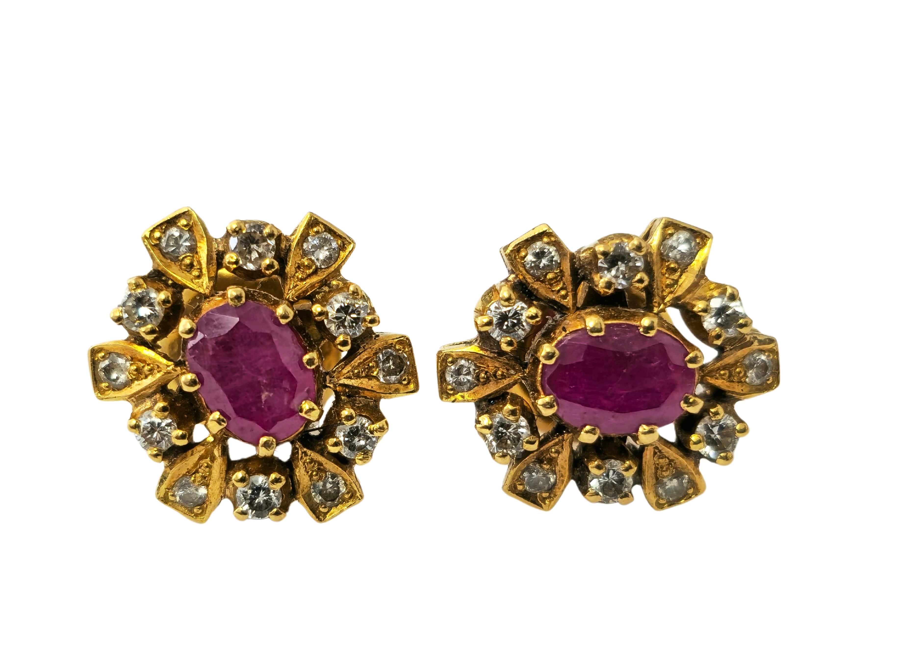 Fabricados en oro amarillo de 18 quilates, estos exquisitos pendientes presentan un impresionante rubí ovalado de 1,20 quilates, rodeado de un total de 1,03 quilates de diamantes redondos de talla única. Los diamantes tienen claridad SI1 y color G,
