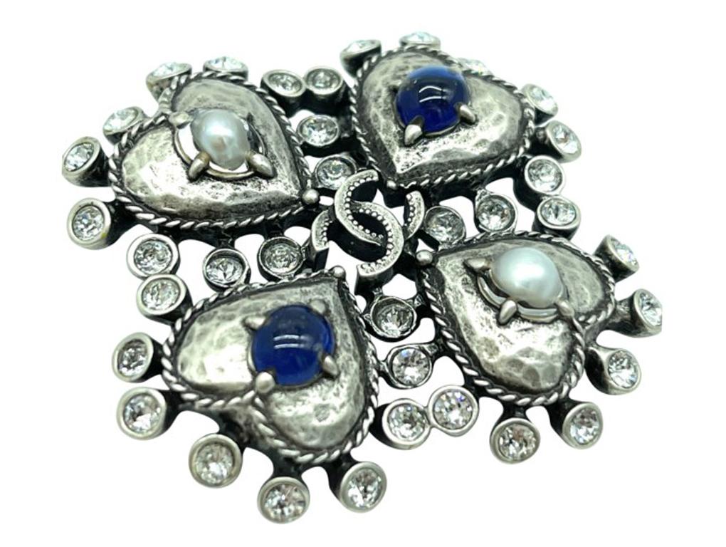 Gorgeous Chanel CC brooch in silver metal with 4 heart  detail. Such a classic which can be worn with anything.

BRAND	
Chanel

ACCESSORIES	
Box

COLOUR	
Silver, blue, white

MEASUREMENTS	
Approx 5cm x 4cm

CONDITION	
New

FEATURES	
silver hardware,