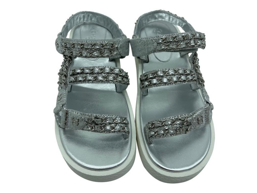 Beautiful and stunning Chanel Silver Dad sandals in silver leather finished off with silver chain detail.

BRAND	
Chanel

FEATURES	
CC logo detail, dad sandals, chain detail

COLOUR	
Silver, white

CONDITION	
New

MEASUREMENTS	
38

ACCESSORIES	
Box,