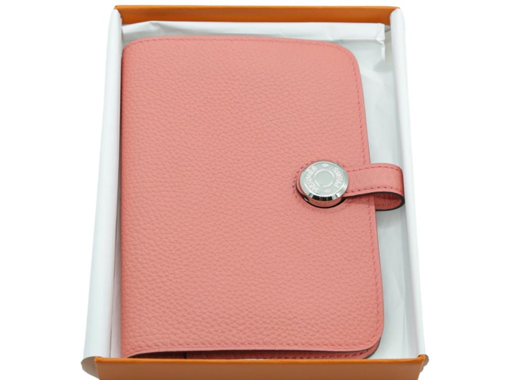 This stylish, classic and timeless Hermes Compact Dogon Wallet is crafted of luxurious togo calfskin leather in Rose Azalee. Only stored since purchase and never used. There are a few indentations on the inside flap where the zip has been lying next