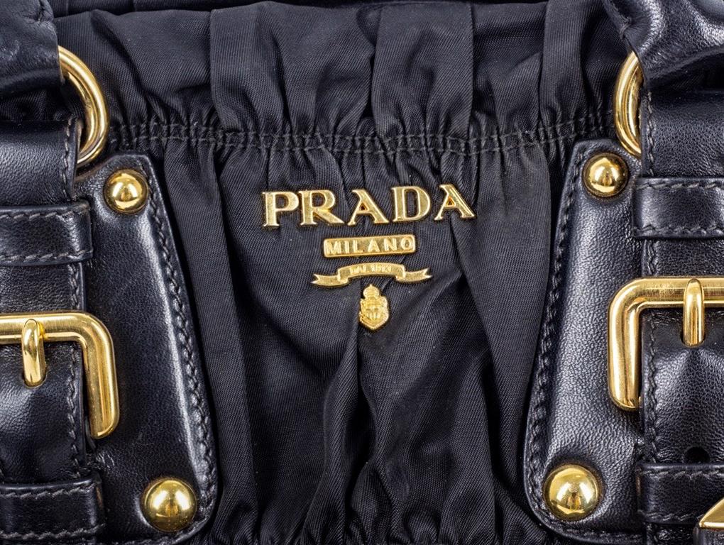 What a lovely Prada bag this is. Made from black nylon and leather in a ruched design. Wear as a Tote, shoulder or cross-body bag. A preloved bag in very good condition, curling to the leather belting of the buckle/ notch detail and minor scratches