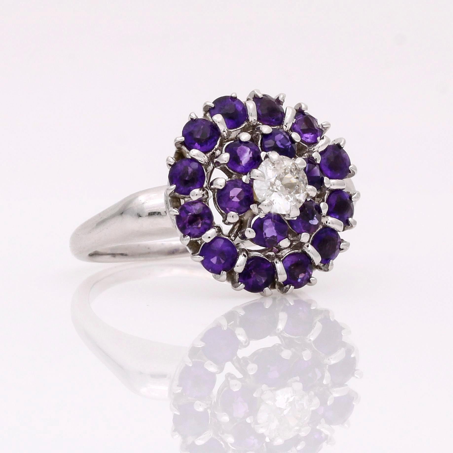 This vintage gemstone and diamond cluster ring is a timeless piece of glamorous jewelry. With a diamond at the center surrounded by two rows of round-cut amethysts, this unique ring adds an eye-catching element to your look. Wear it alone or with