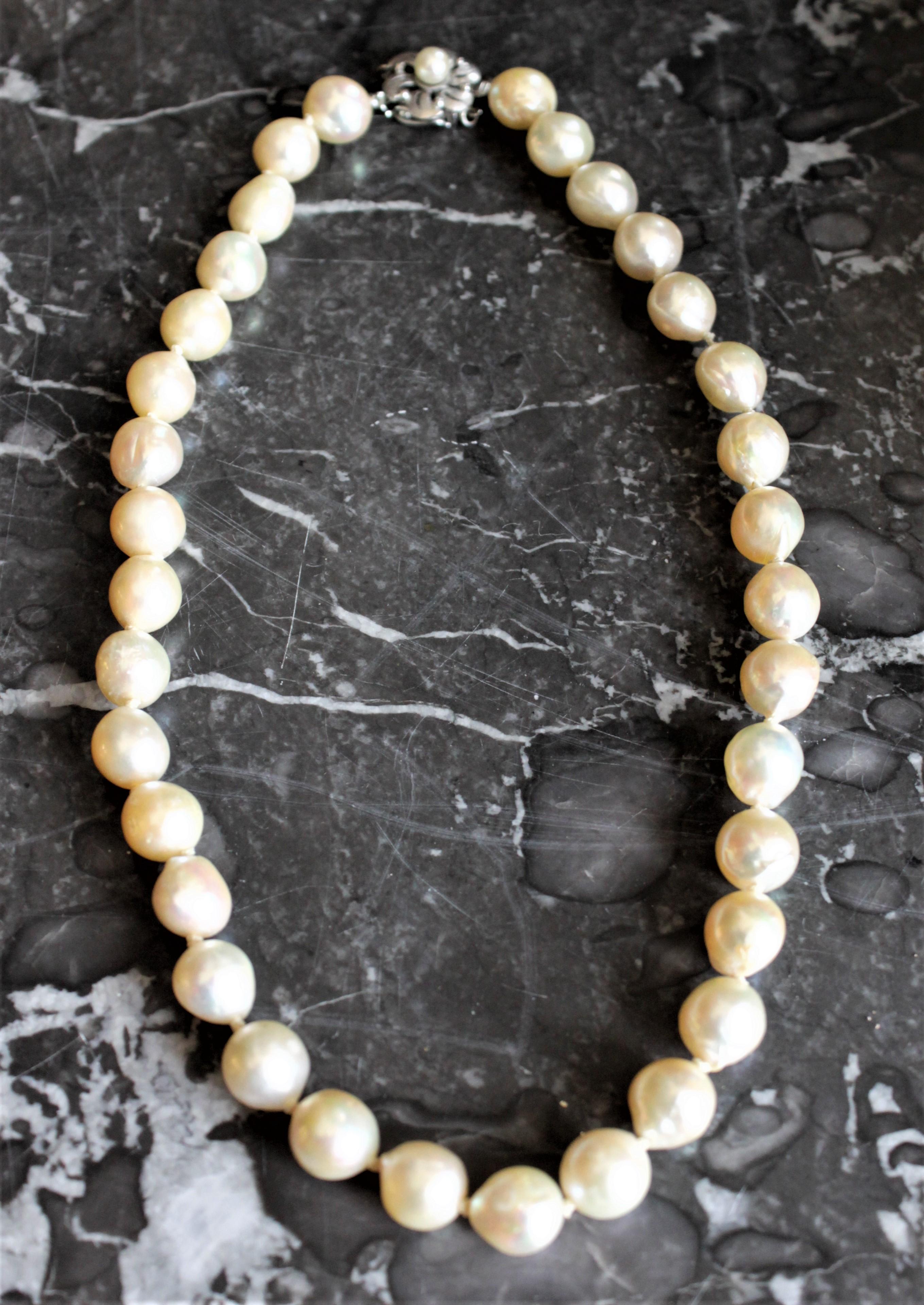 This vintage women's cultured pearl choker necklace is presumed to have been made in North America in circa 1950 in the Baroque style. The pearls are of a good size and well matched with a strong iridescent luster. The pearls are individually hand