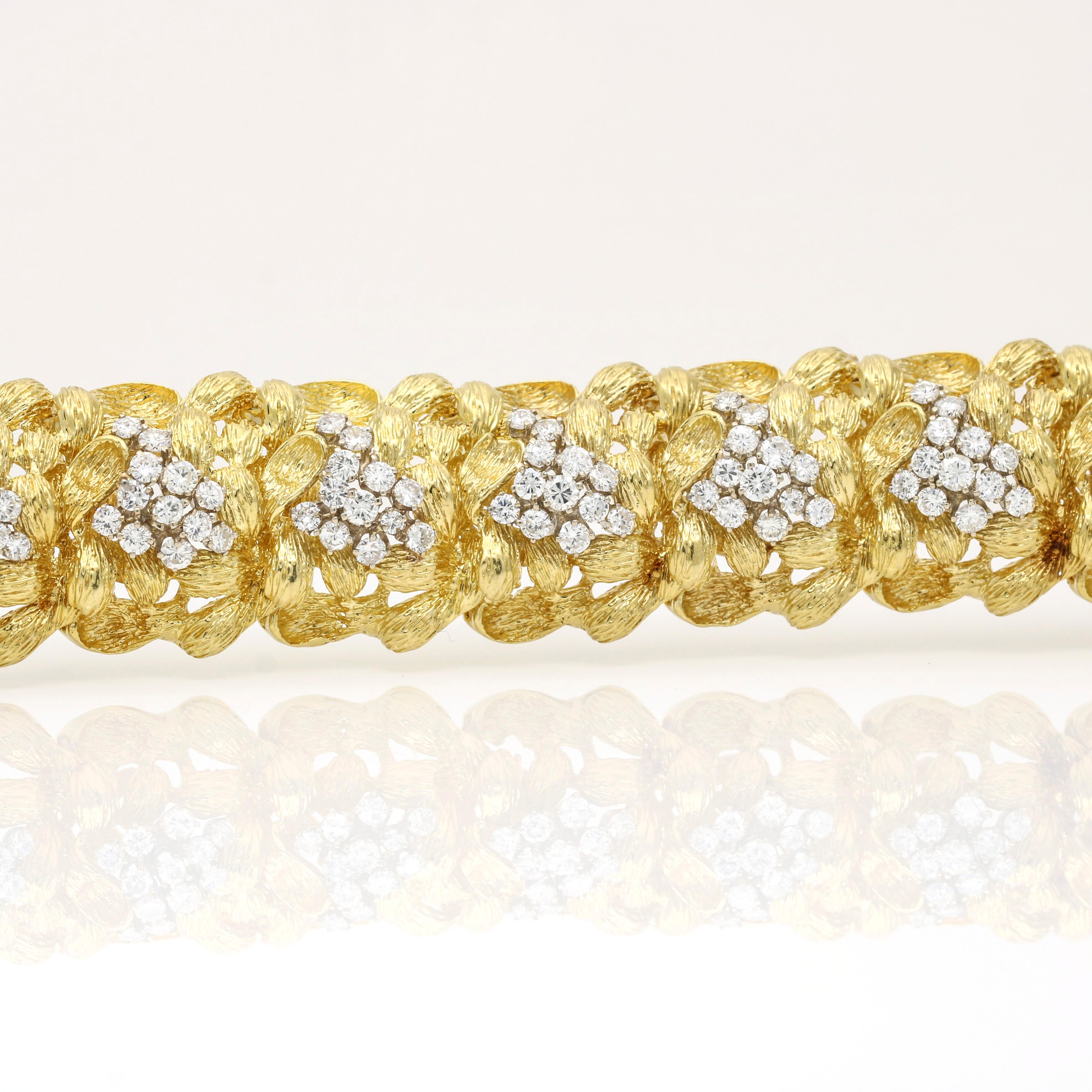 Women's statement link bracelet made of 18K yellow gold from the mid-century era. It has a gold weight of 75.60 grams and features significant, bold links with textured gold resembling leaves. The bracelet is encrusted with dazzling round-cut