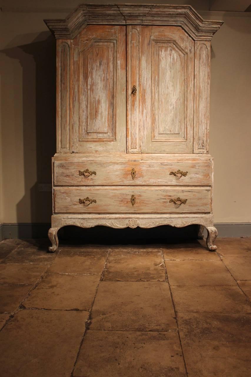 A wonderfully decorative 18th century painted Swedish cupboard, scraped back to its original paint with great proportions and patina, that will work well in most settings. The upper-section enclosing shelves and drawers, the base section with