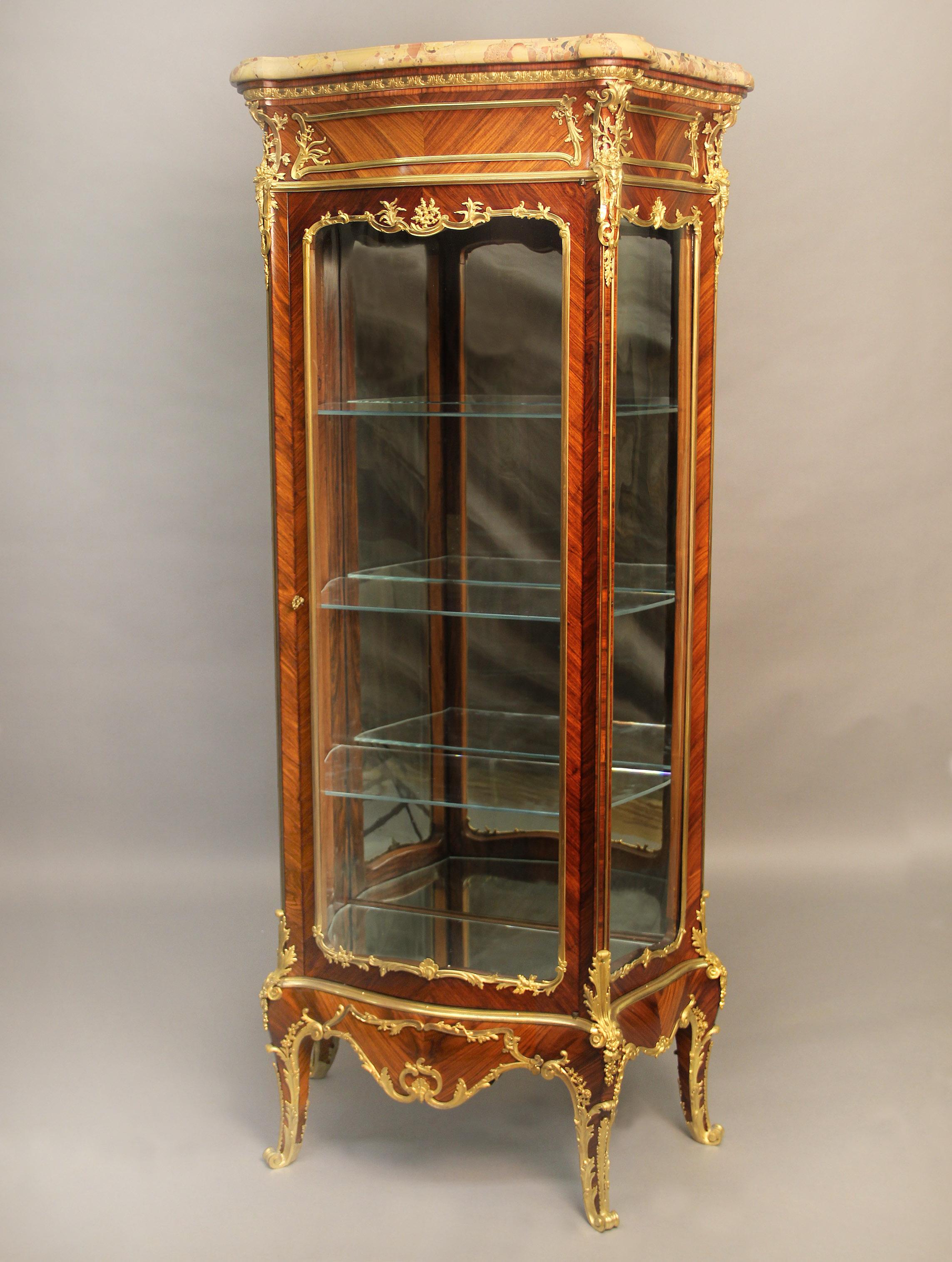 A wonderful late 19th century Louis XV style gilt bronze mounted vitrine by Joseph Zwiener.

Joseph Zwiener

The serpentine-shaped brèche d’ alep marble top above a single centered glass door, flanked to each side by a conforming panel, the