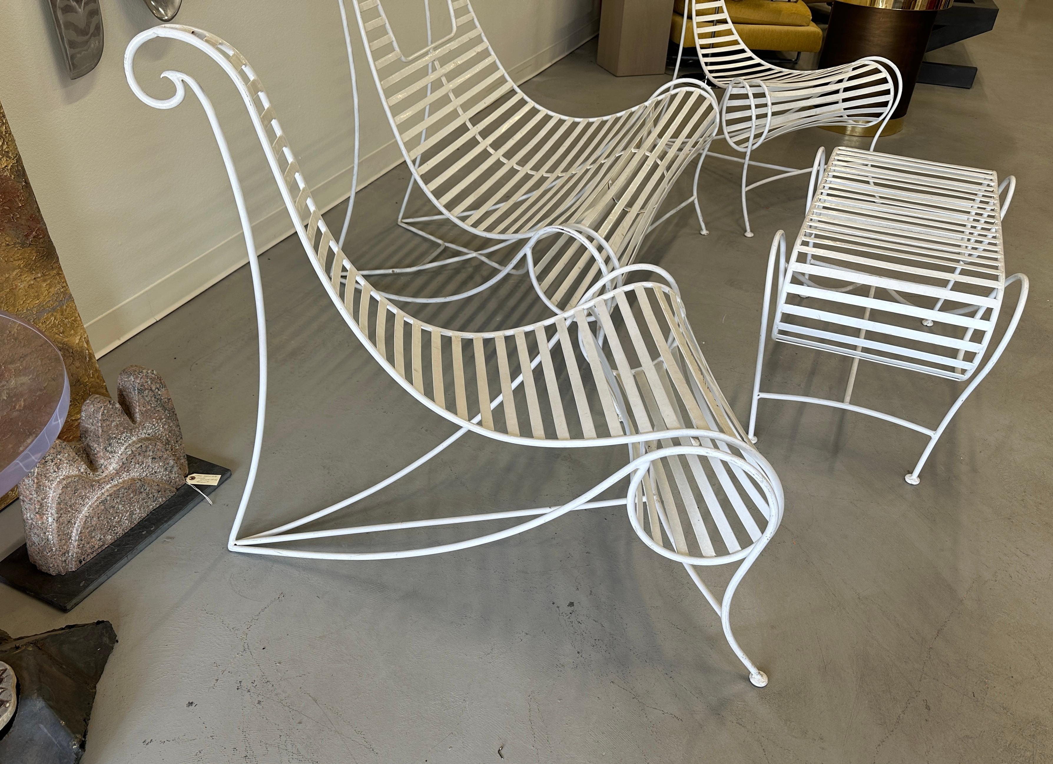 Wonderful 4 piece wrought iron set after a design by Andre Dubreuil. 2 lounge chairs, a settee and a small table. Great sculptural presence. In white paint. Some paint loss and wear please see the detailed photos. 
Table dimensions are 36 inches