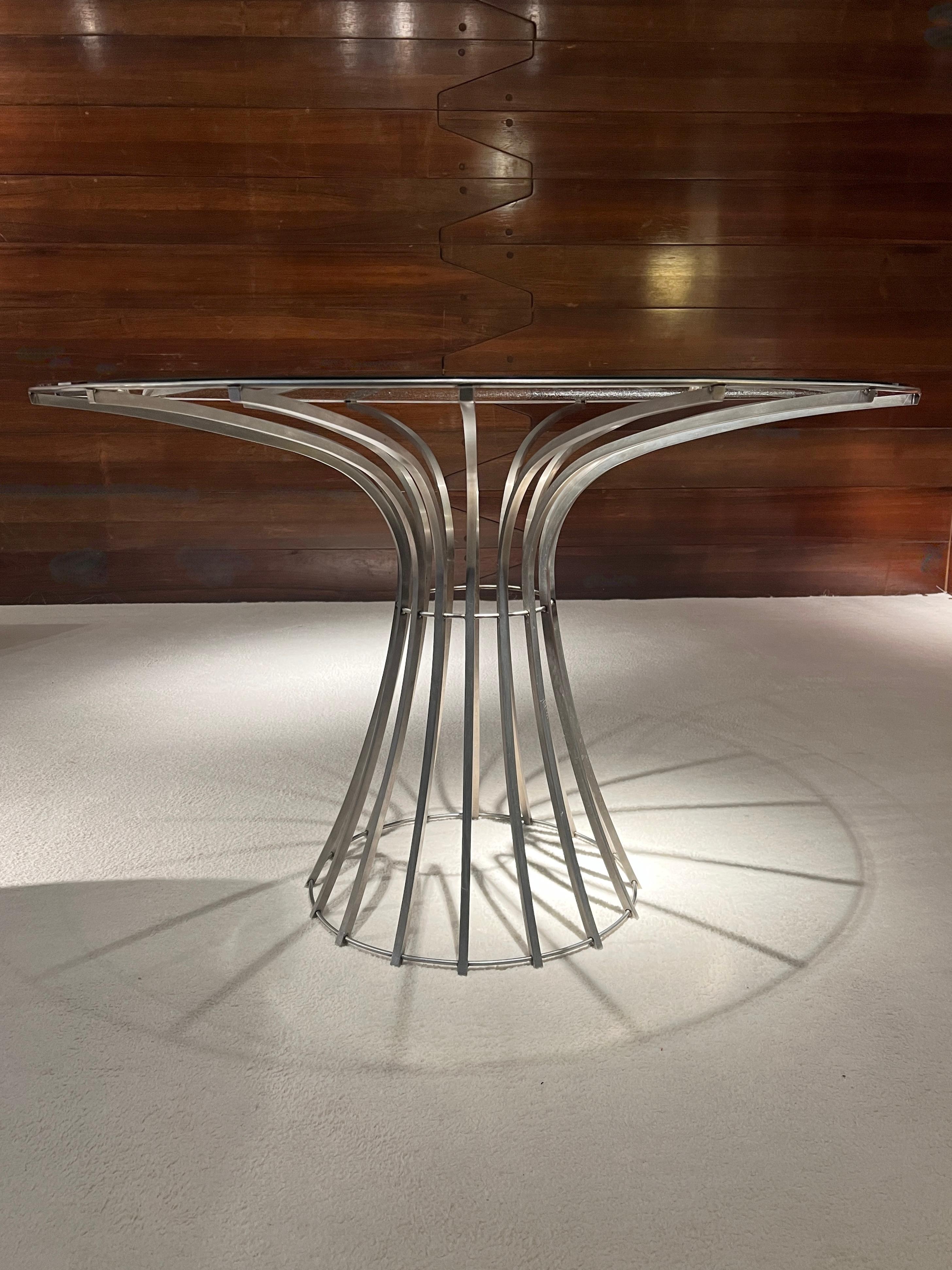 Outstanding table designed by French designer Xavier Fréal. 
This airy design is based on an aesthetic construction with an architectural spirit. The slender, curved steel legs support the glass top with lightness and elegance. This table, which can