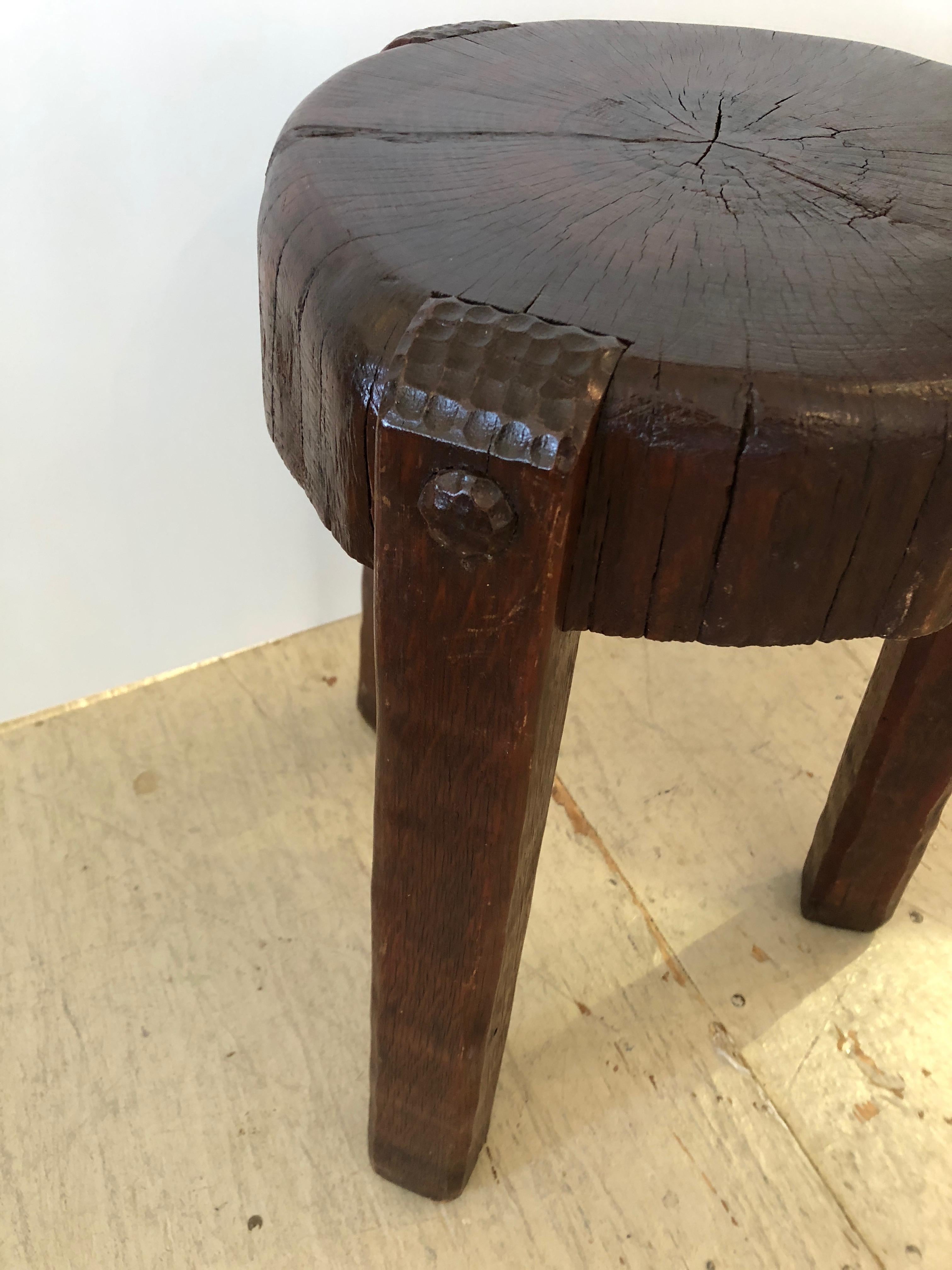 Beautifully crafted handmade Primitive Arts & Crafts folk style round end table or drinks table having a thick oak slab top with gorgeous grain. The legs have wooden pegs and wonderful carving at the top.