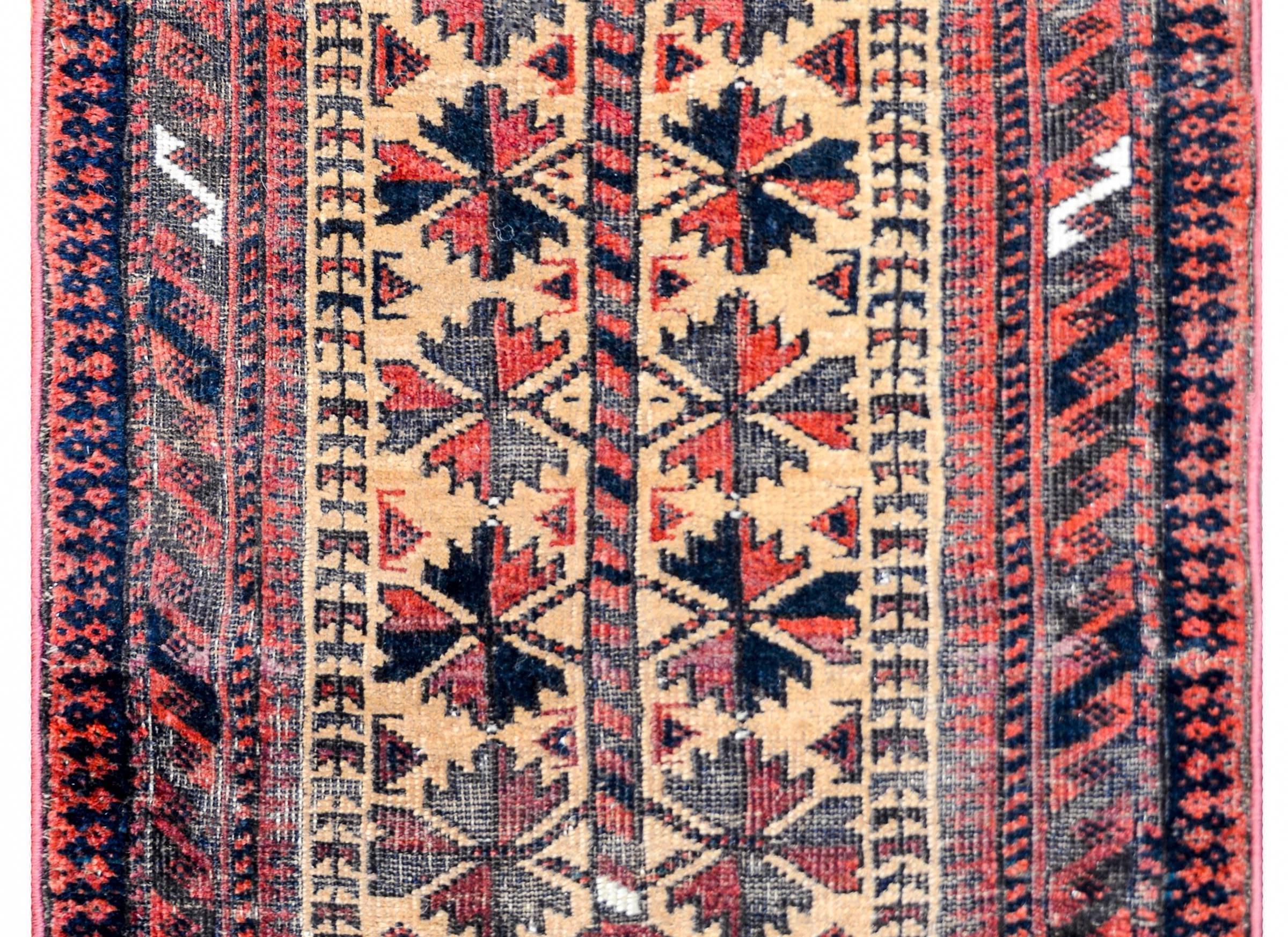 A wonderful early 20th century antique Persian Baluch rug with an all-over leaf pattern woven in crimson, black, and green, on a gold background, surrounded by a wide complementary geometric border.