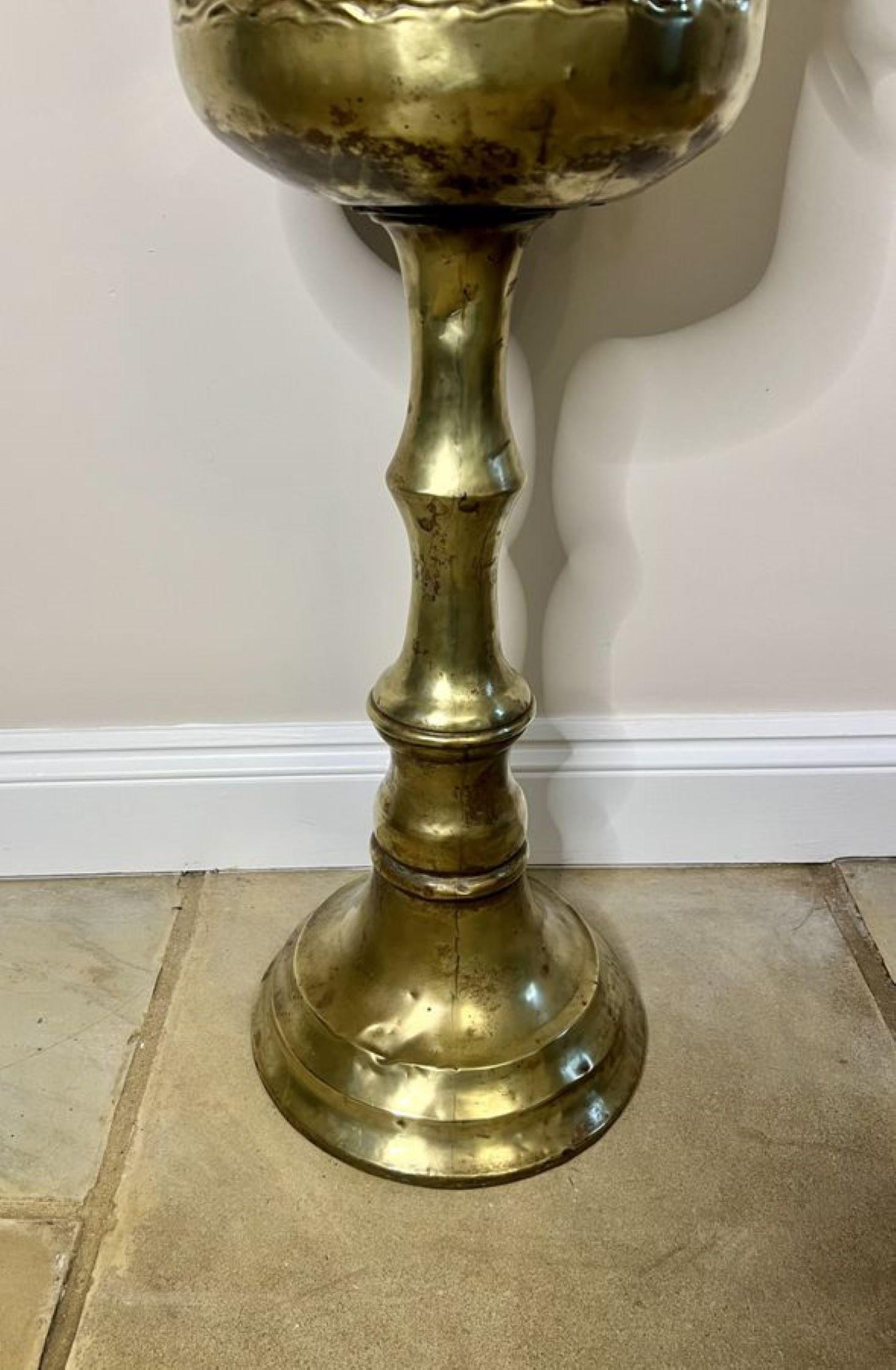 Wonderful antique Edwardian Dutch brass champagne bucket on a stand having a superb quality Dutch antique champagne bucket on a stand with a circular embossed brass champagne bucket with a ship to the front and lion heads ring handles to both sides,