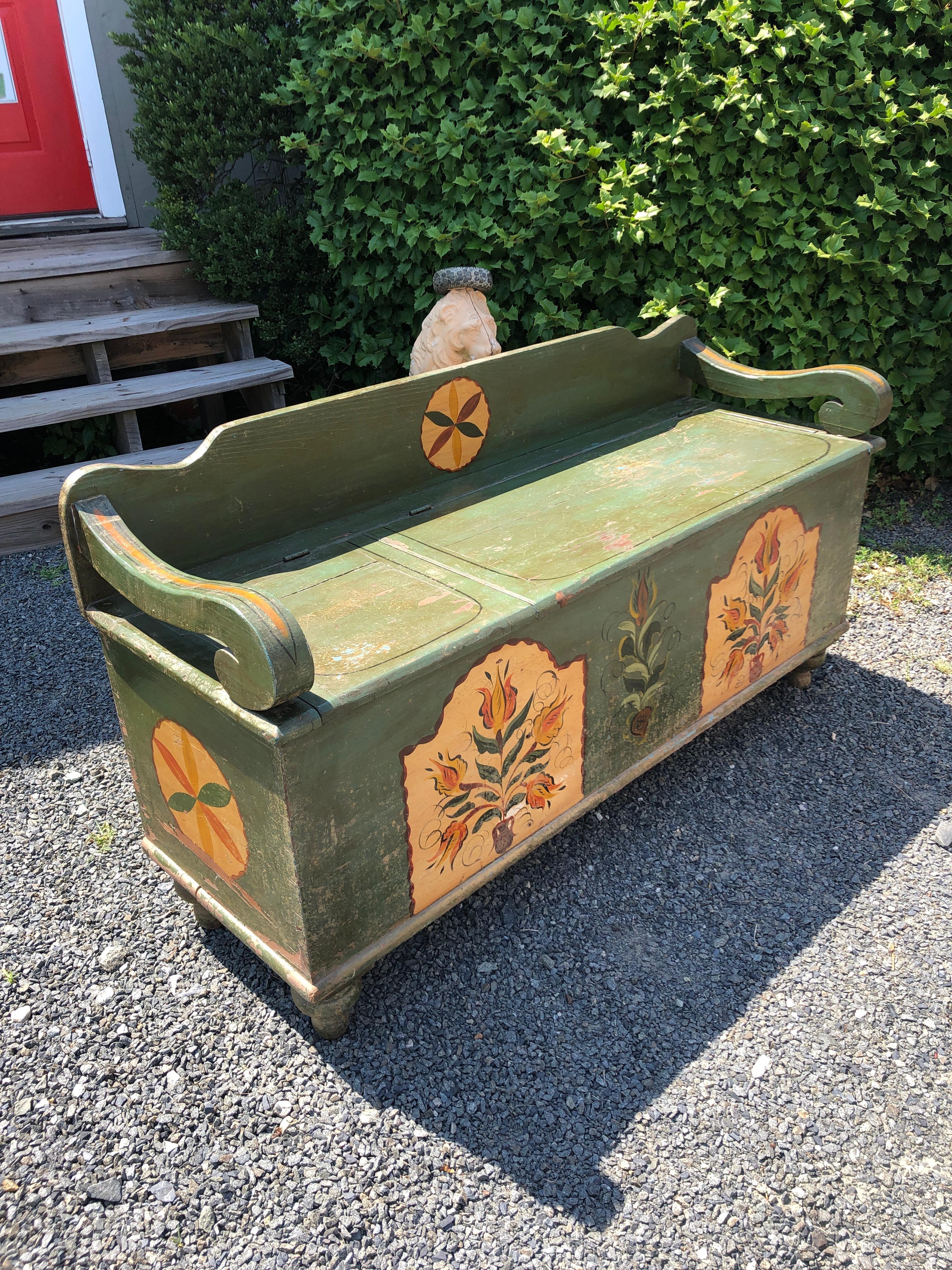Hand painted rustic distressed earthy green Amish bench having country style decoration in light gold, green and orange. The seat lifts up in two panels to reveal functional storage inside. Would be great in a mudroom or hallway.
Measures: seat