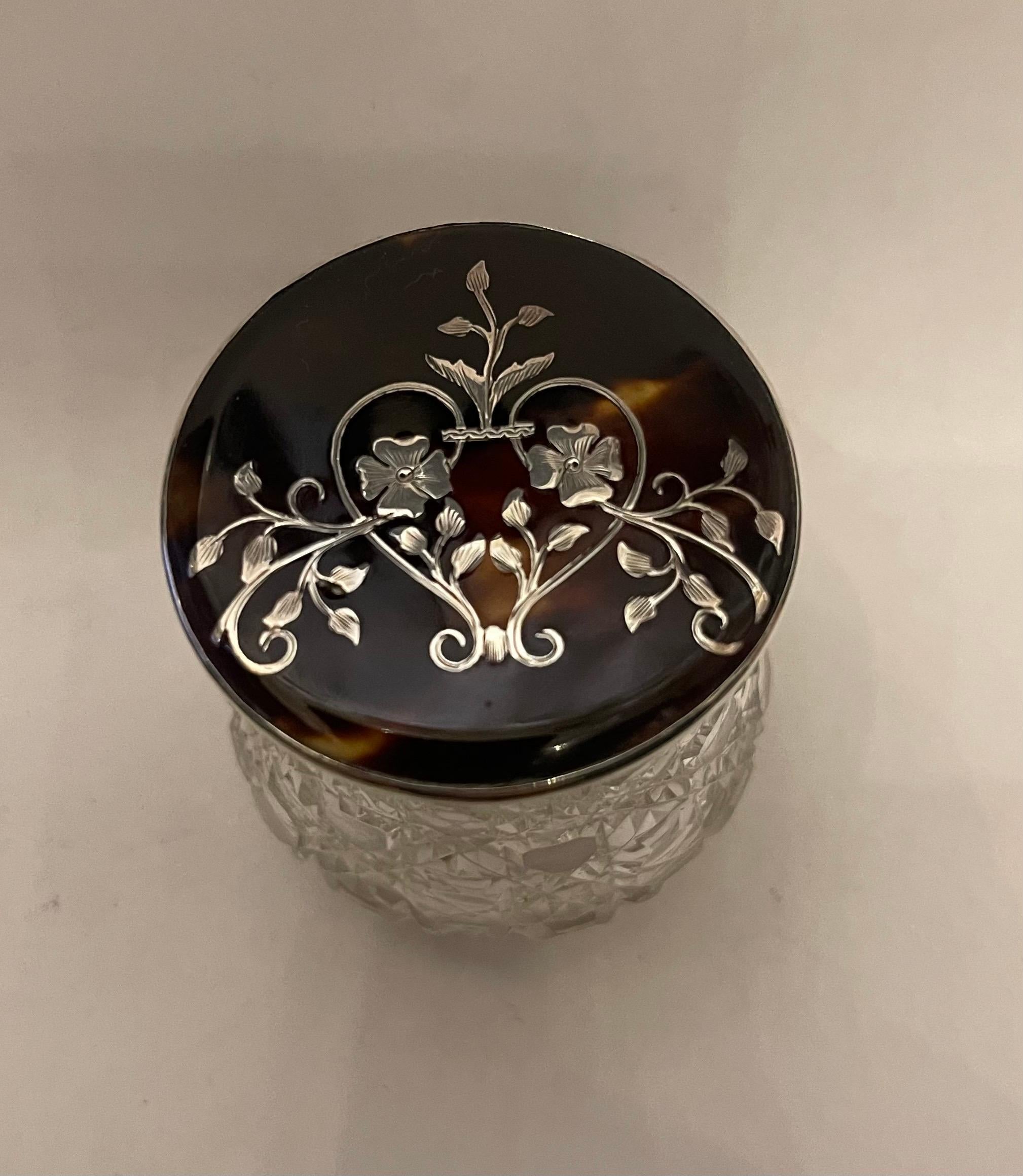 A Wonderful Small Round Sterling Silver And Tortoise Shell Vanity Powder / Trinket Box Or Jar. The Sterling Silver Top Having A Tortoise Shell Pique Inlaid With Removable Lid With English Silver Marks. The Clear Cut Crystal Bottle Has Been