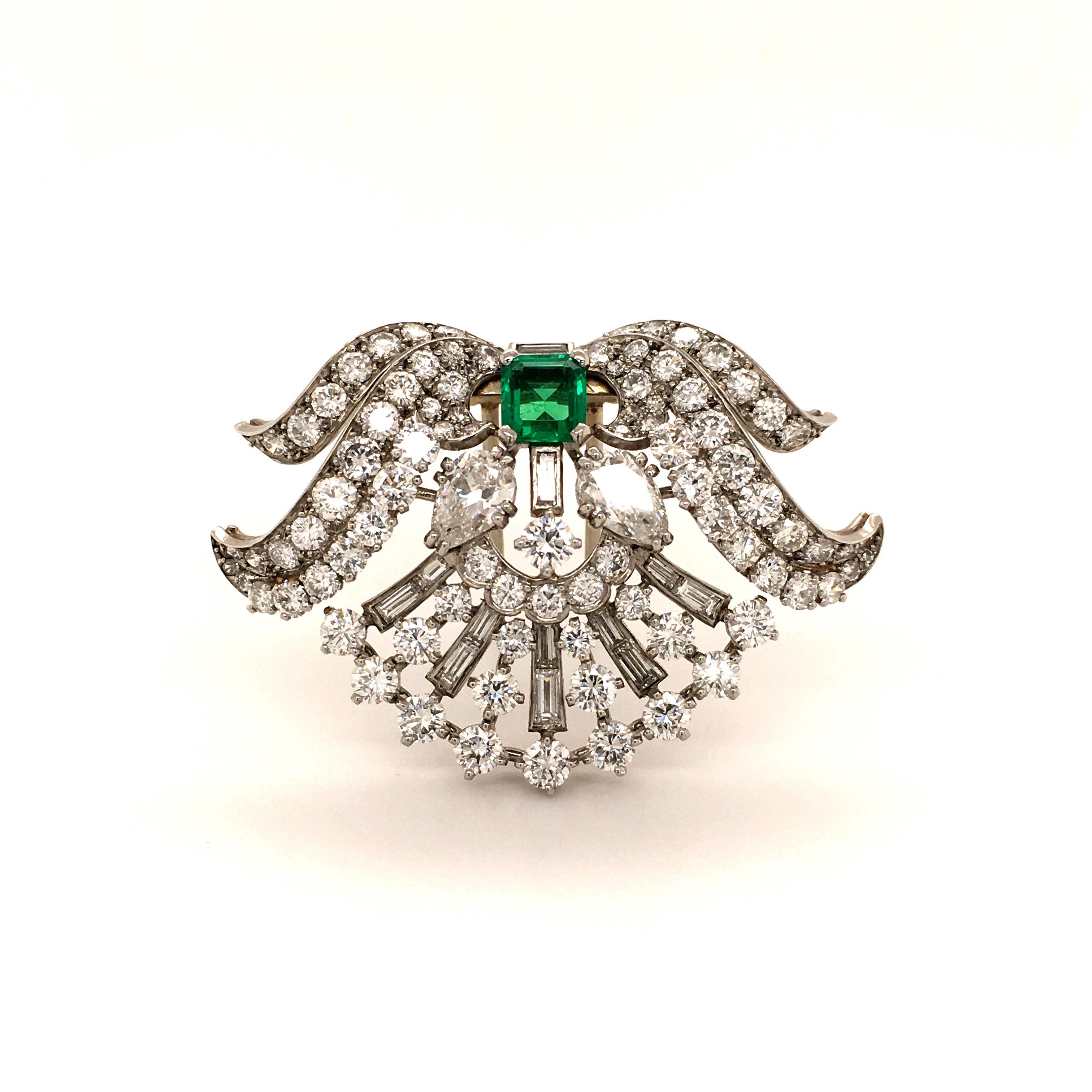 This beautifully curved clip impresses with its elegant French design. 
It is set with an exceptionally clear 0.90 ct Colombian emerald of great color. Emeralds of this quality are considered to be rare. 
The brooch is decorated with two charming
