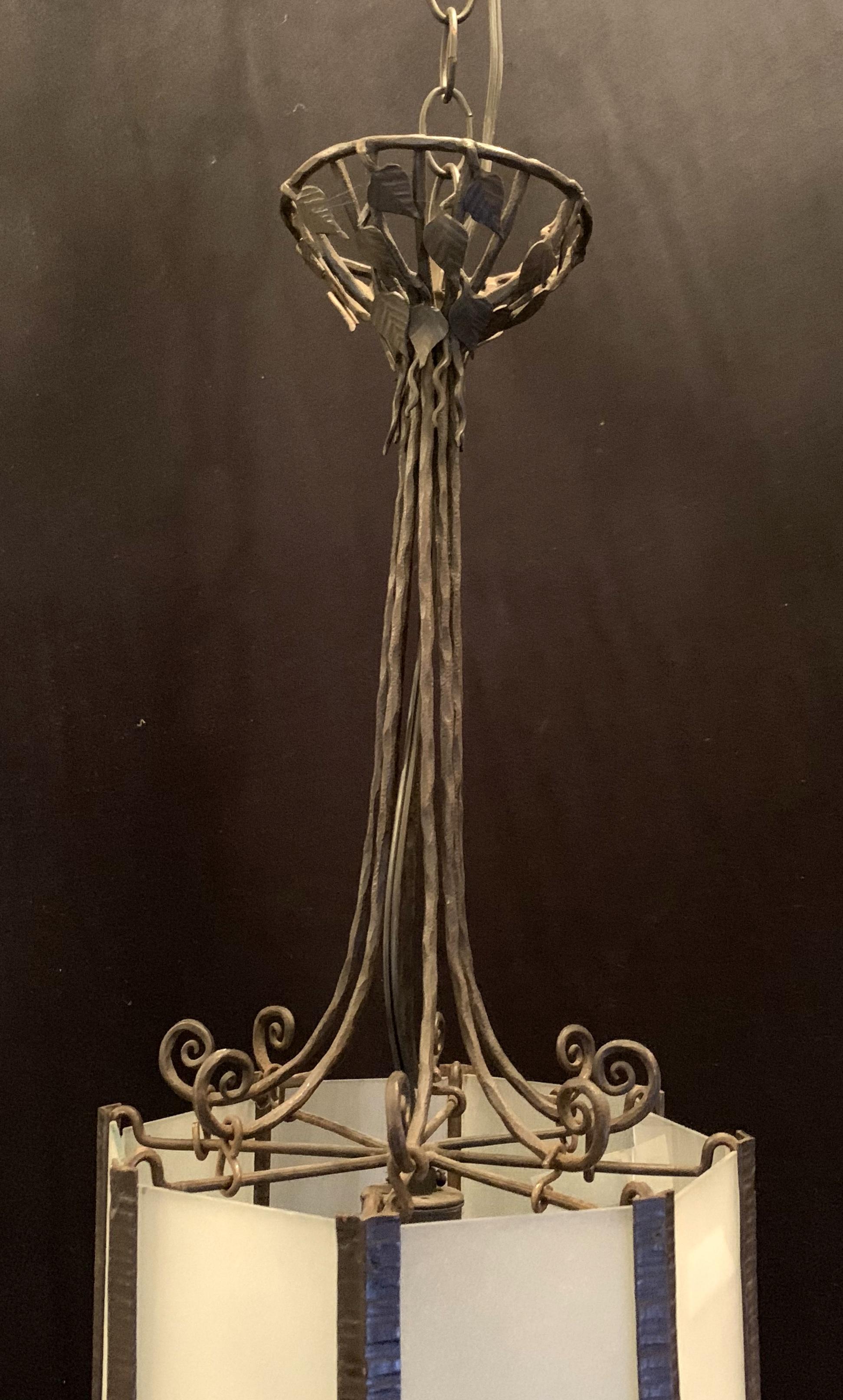 A wonderful art deco scroll, flower & leaf iron & frosted glass lantern fixture with single edison light in the manner of Edgar Brandt.
